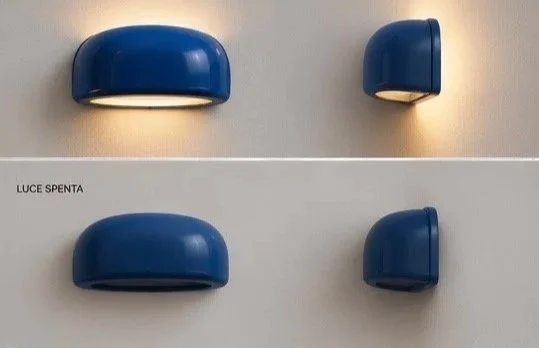Two pairs of blue wall-mounted light fixtures on a beige wall, with the words 'LUCE SPENTA' printed on a white strip.