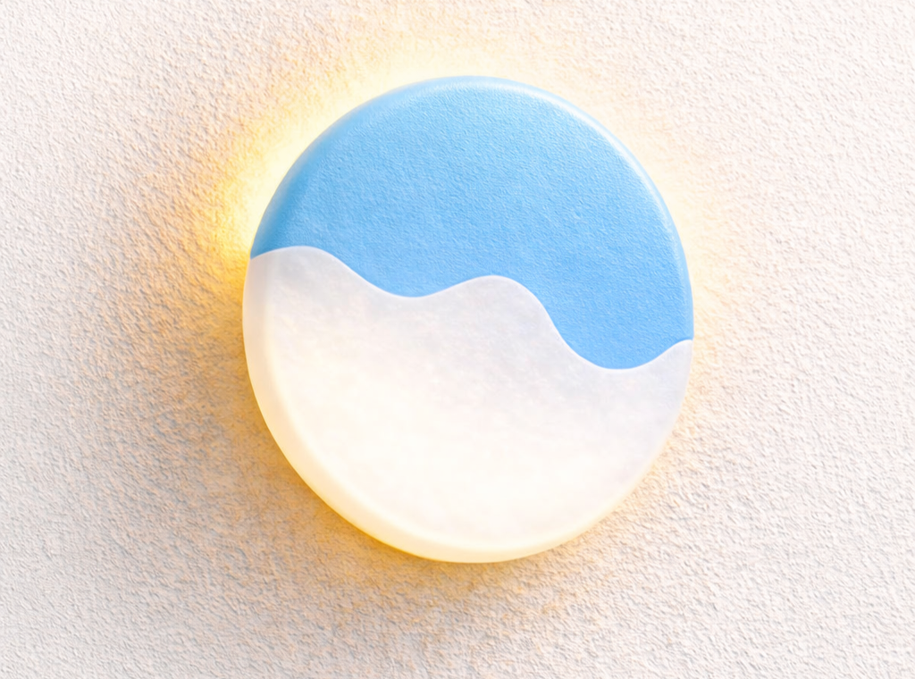 A round lighted wall sign with a blue top half and a white wave shape at the bottom, resembling a stylized ocean or sky scene.