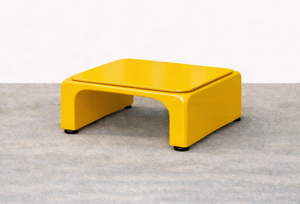 Bright yellow modern coffee table with curved design, placed on a neutral carpet in front of a white wall.