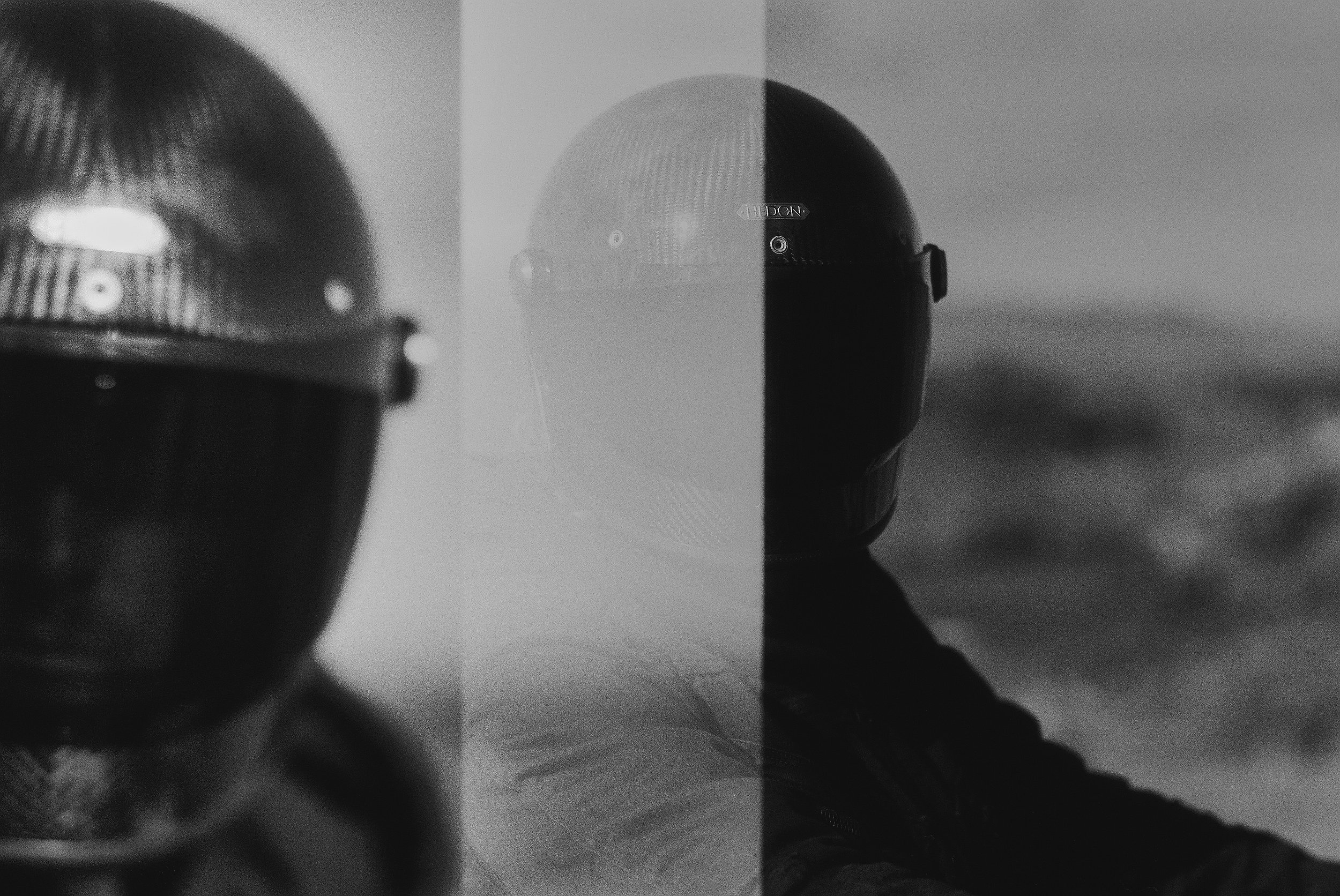 Black and white photograph of a helmet reflected on a mirror surface with a dividing line in the middle, creating a split effect.