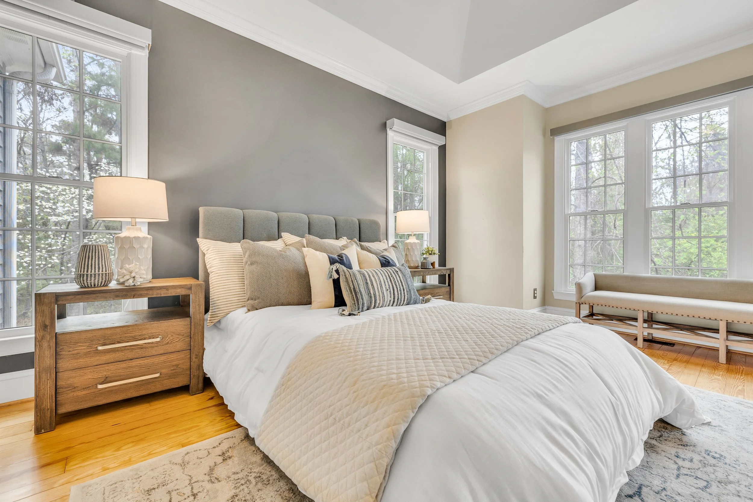 Large bedroom staged with a bed and bench sitting area