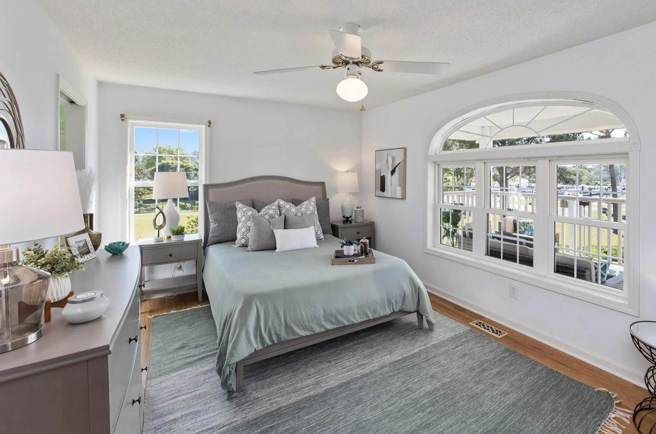 Soft blue bedroom with neutral furnishings and natural light in a staged Wilmington, NC home