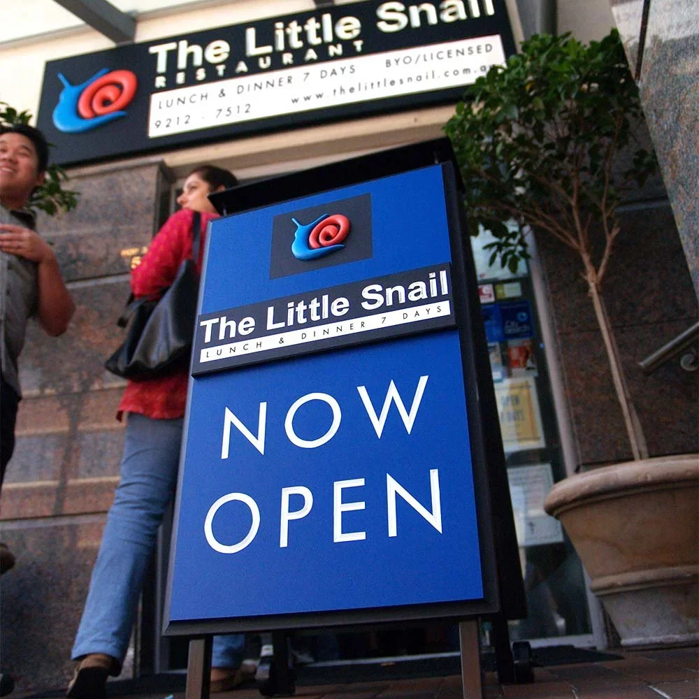 the-little-snail-french-restaurant-walk-in-sidewalk-sign.webp