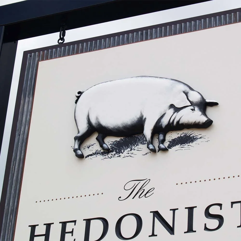 the-hedonist-winery-sculpted-pig-detail-on-sign.webp