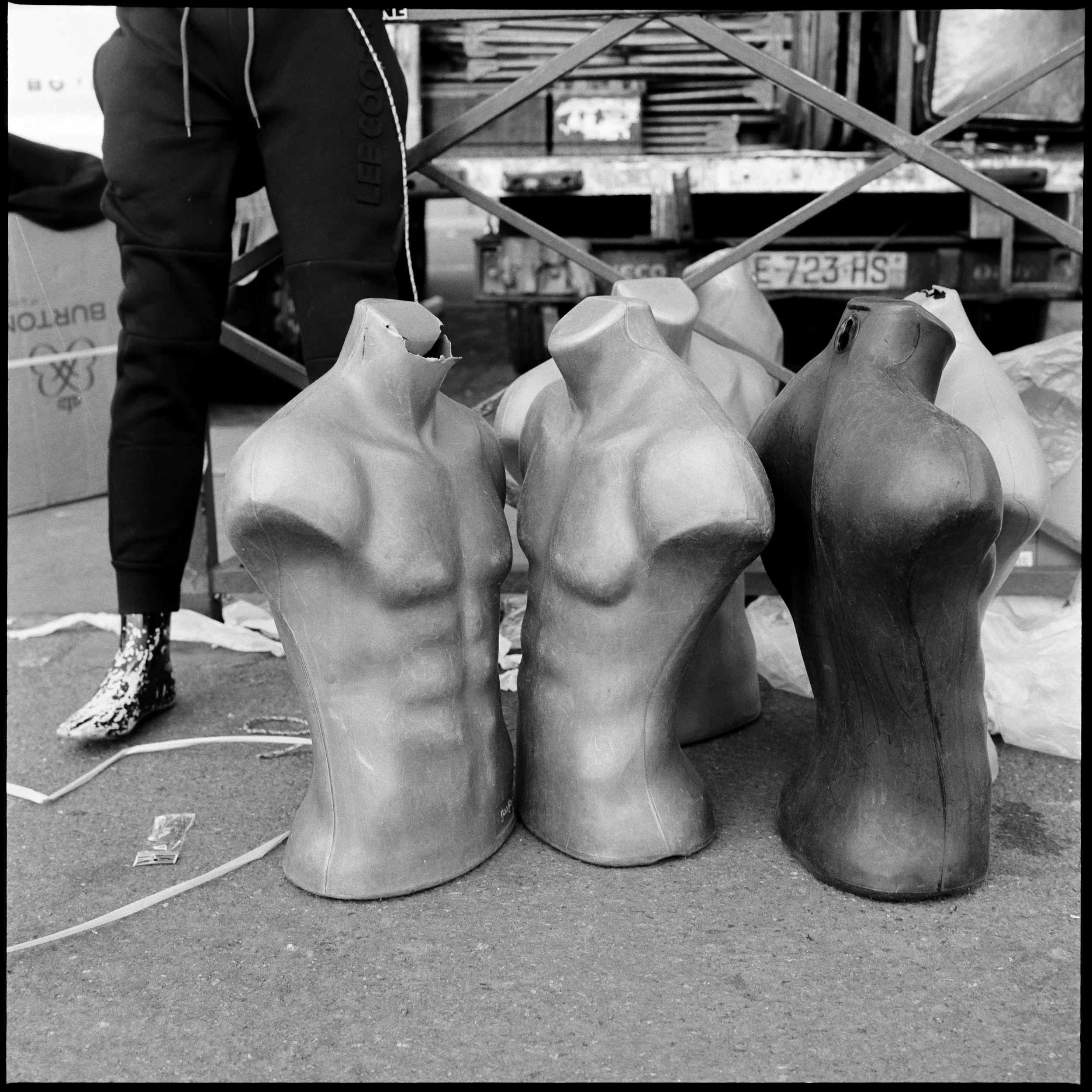 Trois mannequins en torses masculins en matériau synthétique, positionnés sur le sol, avec un fond de lieux de stockage ou atelier.