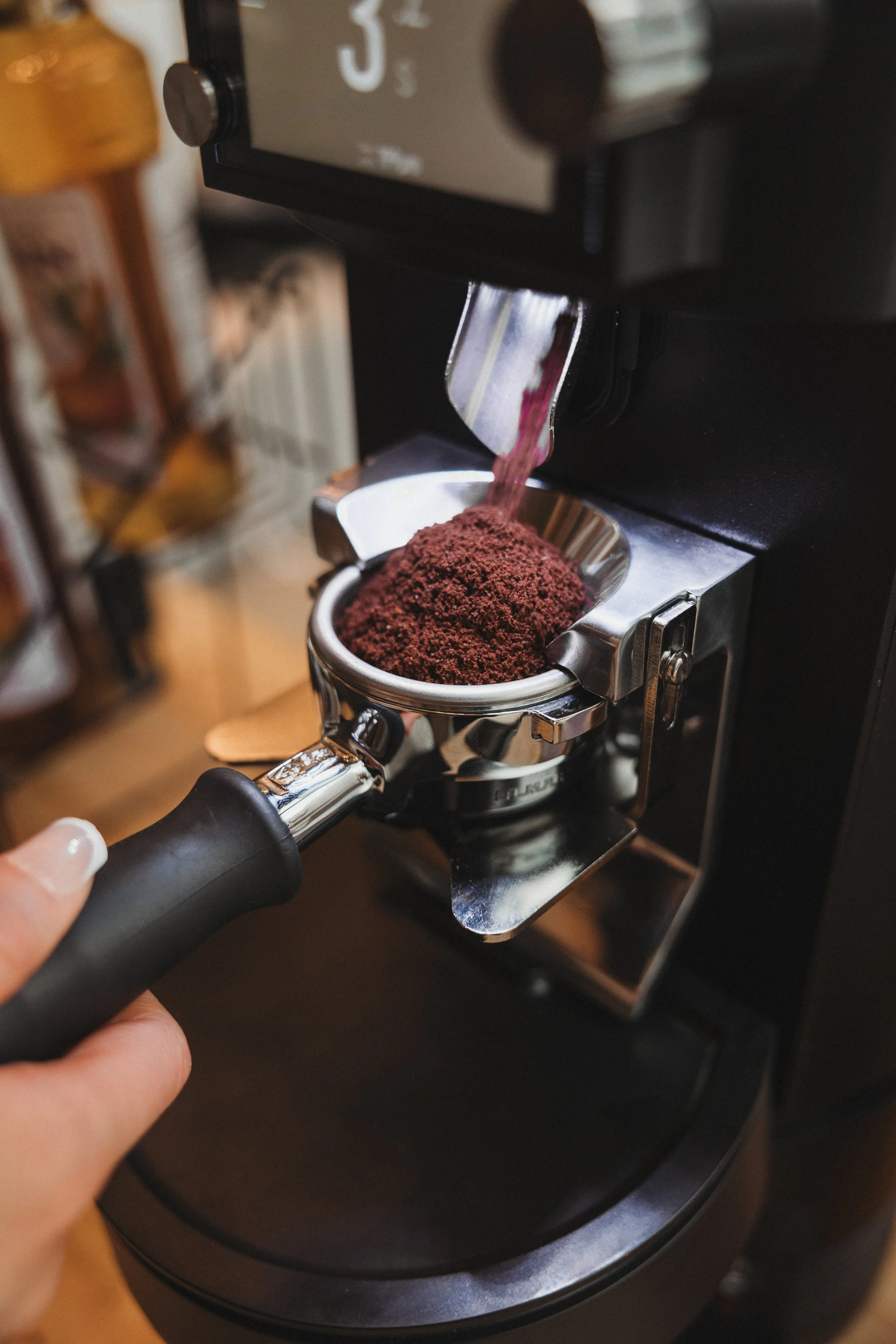 A coffee grinder with ground coffee being dispensed into a portafilter.