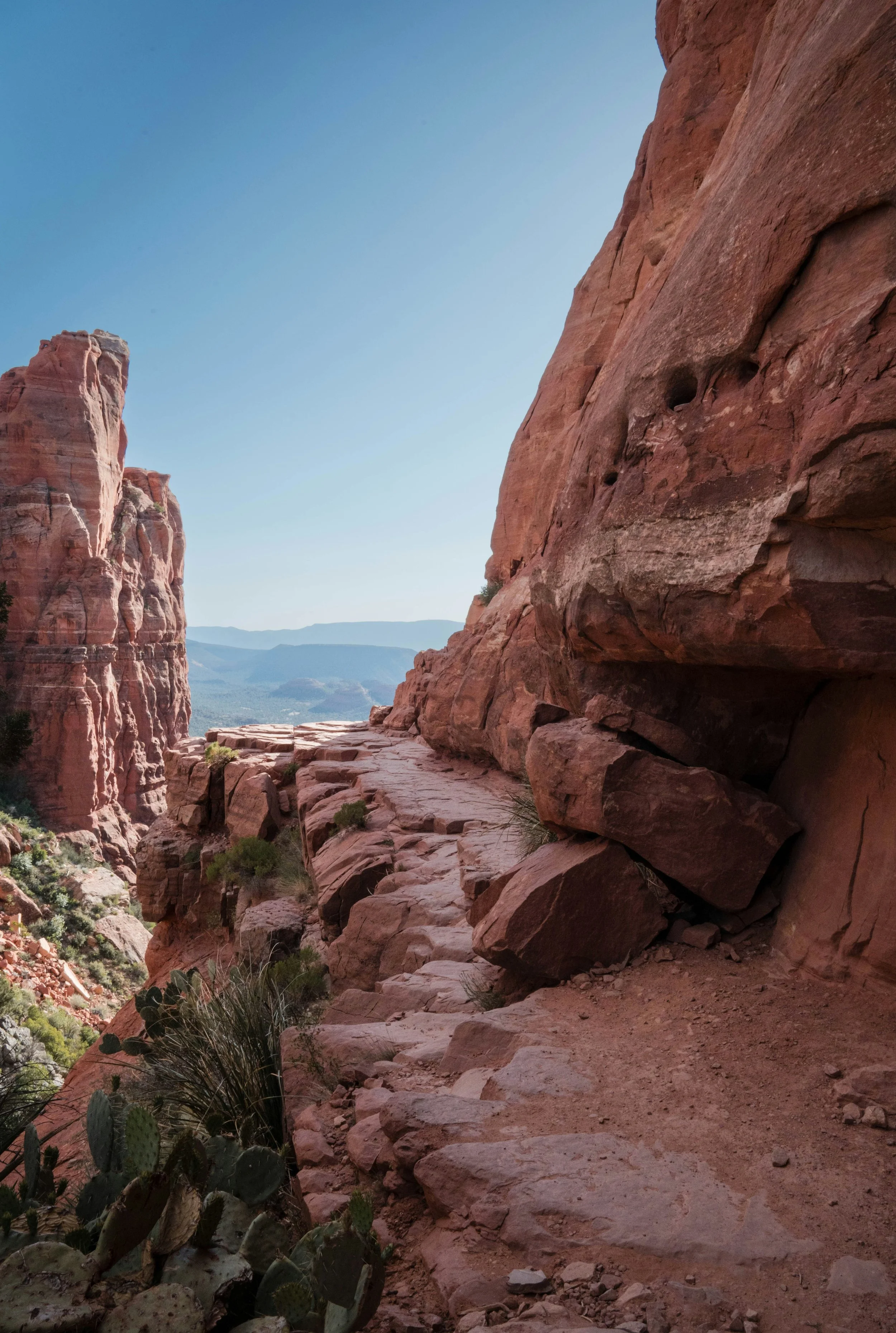 Sandstone path along a rocky slope with red rock cliffs in the distance