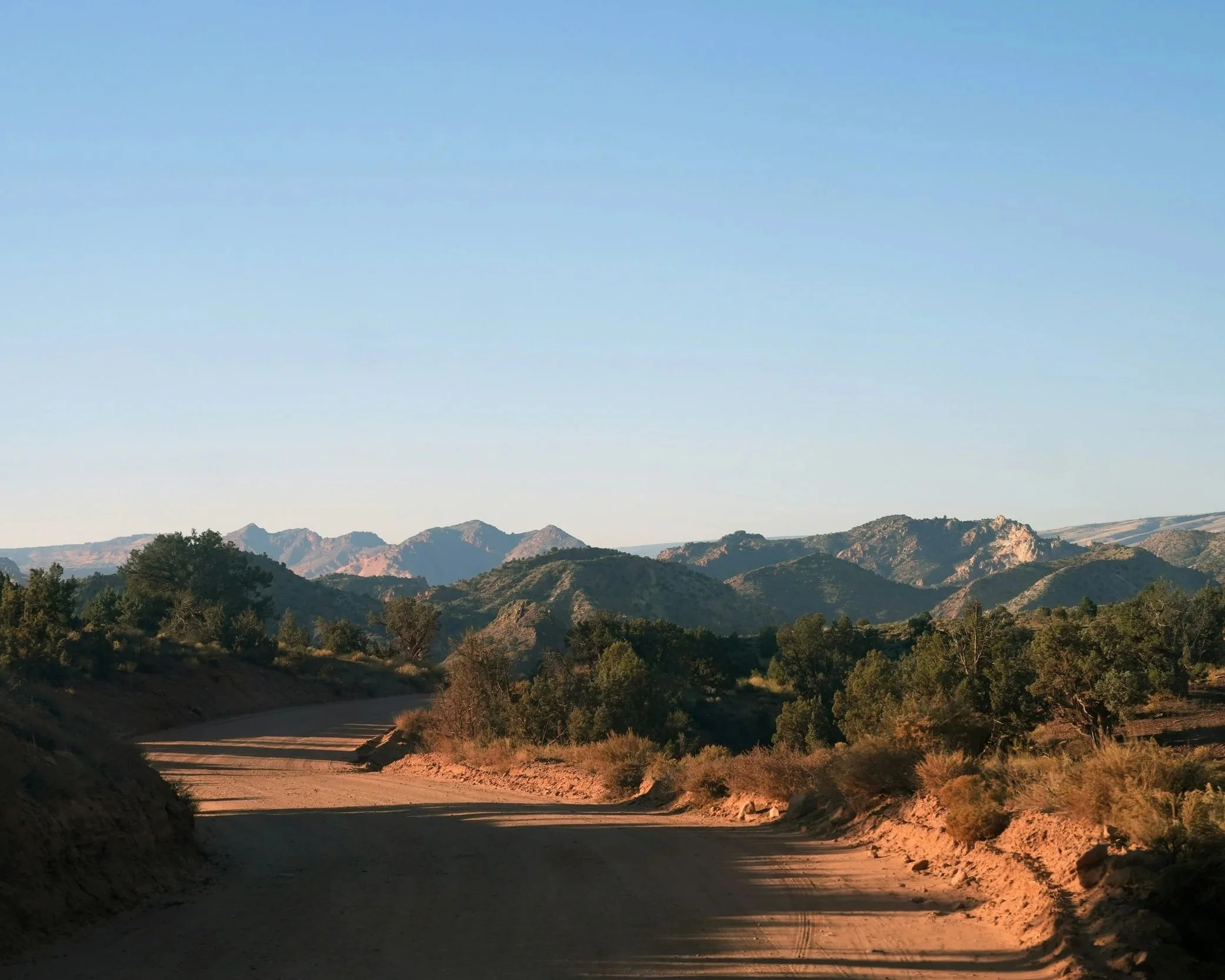 Dirt road winding through desert hills at golden hour