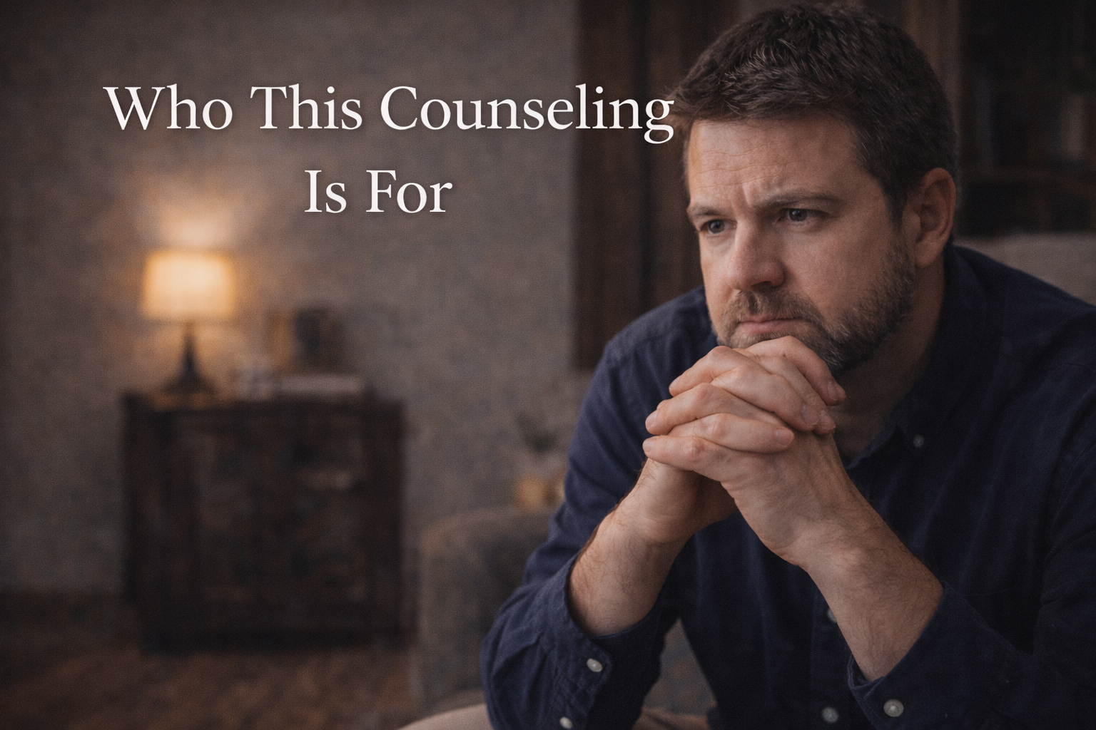 A man with a beard and short hair sits with his hands clasped and his chin resting on them, looking contemplative in a dimly lit room with a lamp and a wooden cabinet in the background, overlaid with white text that reads, "Who This Counseling Is For."