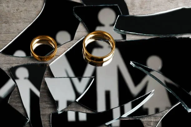 Broken mirror with two gold wedding rings placed on it.