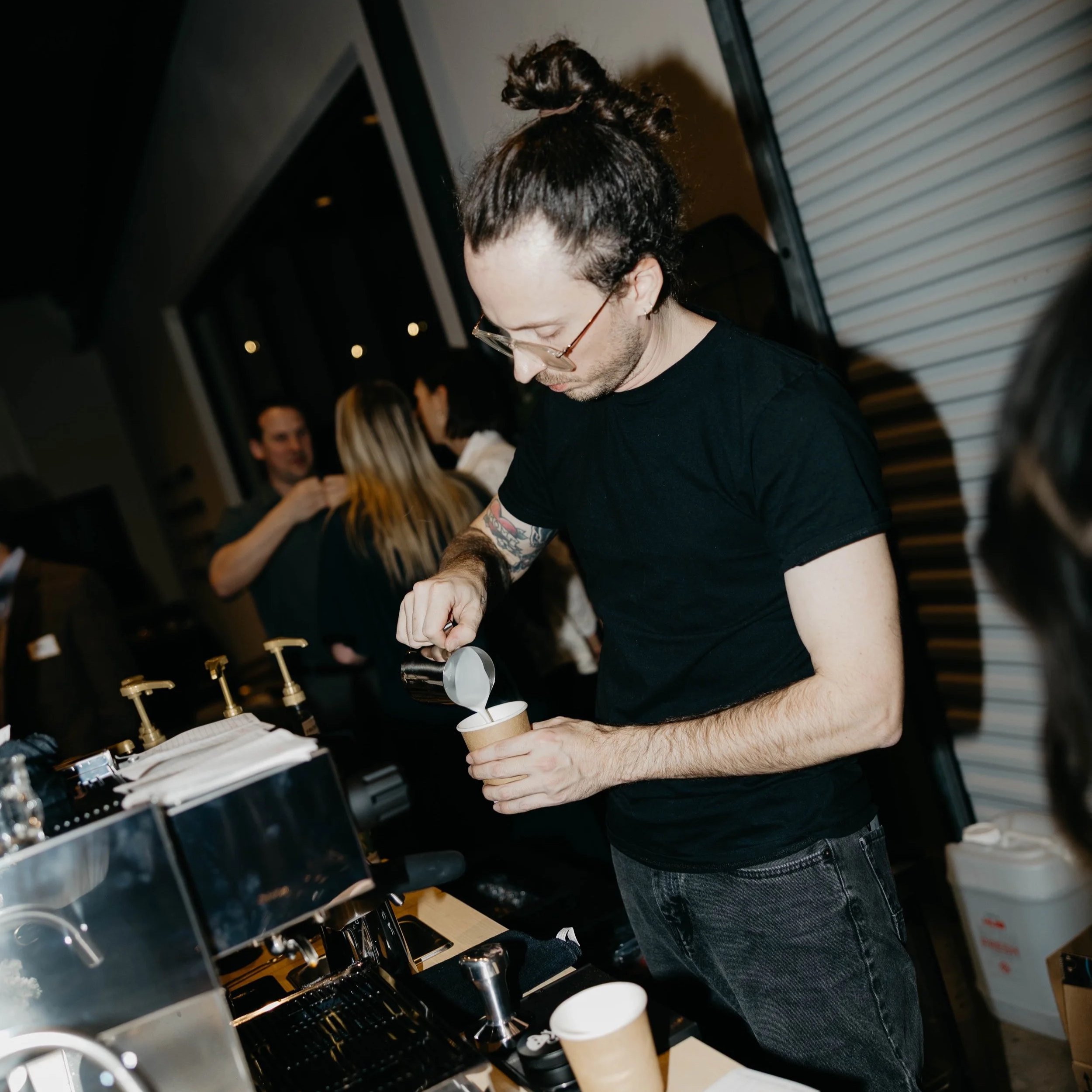 Pouring latte art at church holiday party. Professional La Marzocco Espresso machine on coffee cart.