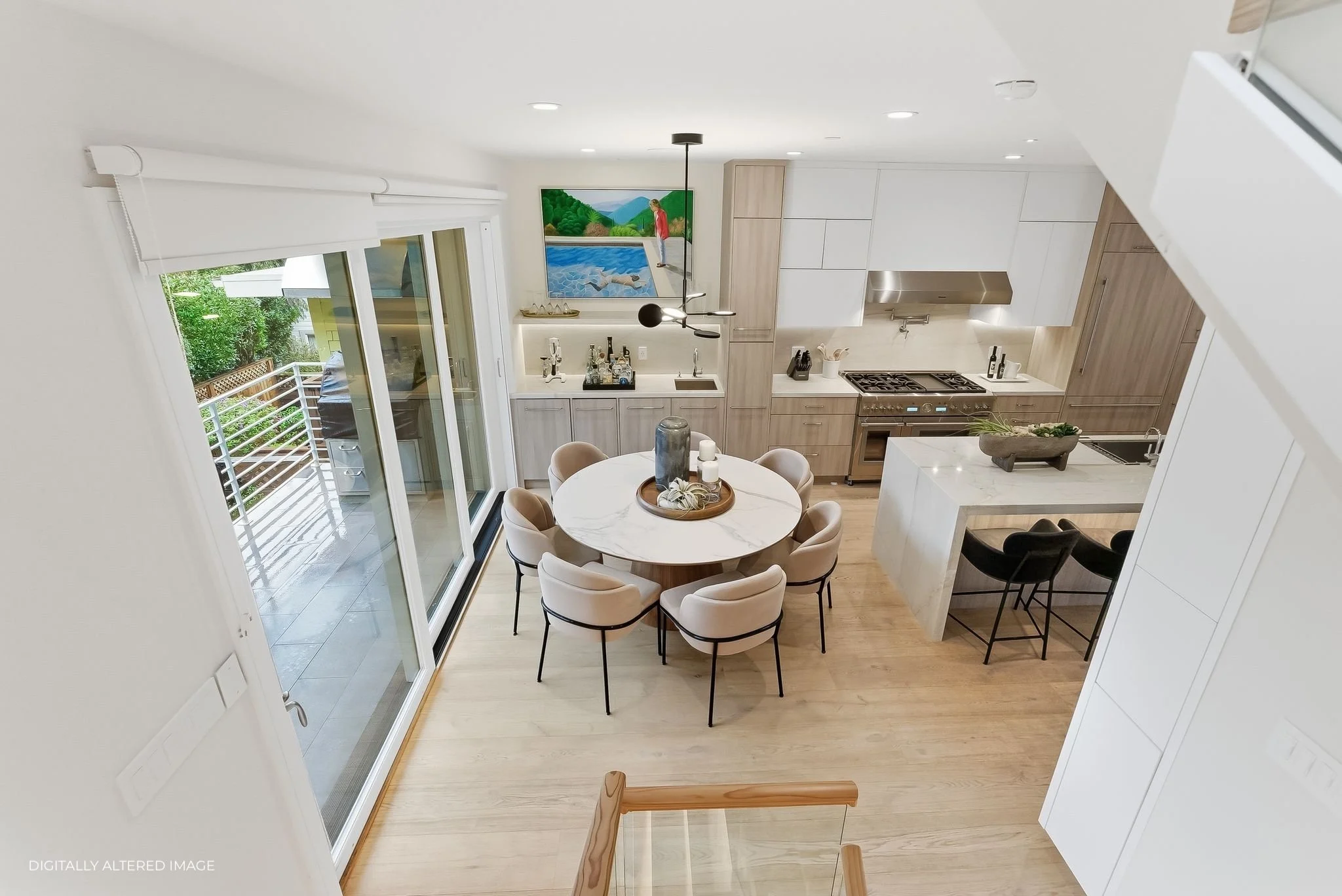 Modern kitchen and dining area with a round table, white chairs, sliding glass door leading to outdoor space, and neutral-colored cabinets and countertops.