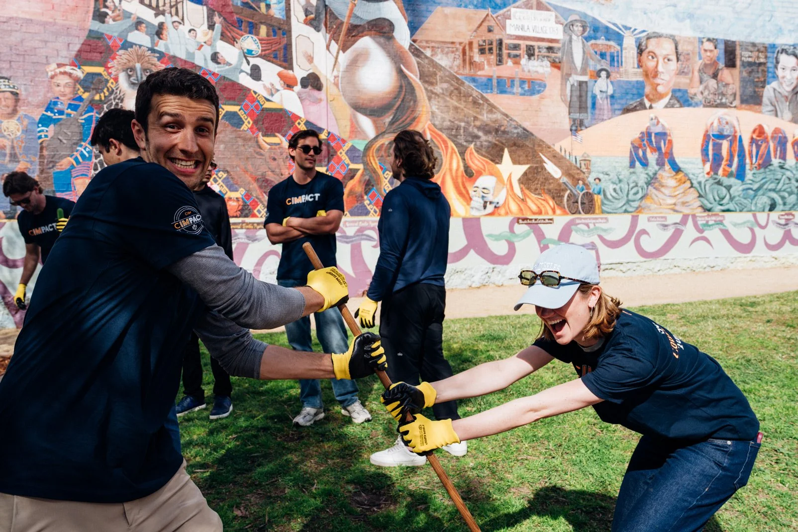Photo of two people wearing CIMPACT shirts digging up a hole together