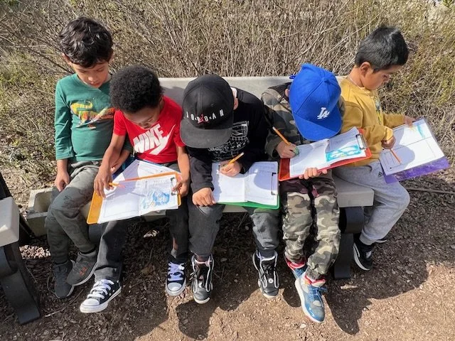 Photo of young students looking at books in the garden.
