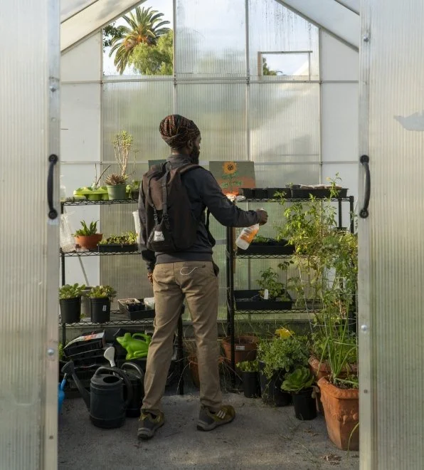 Photo of Chef Korby Benoit inside a green house watering plants