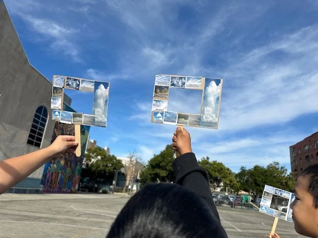 Photo of students holding up handmade frames to the sky