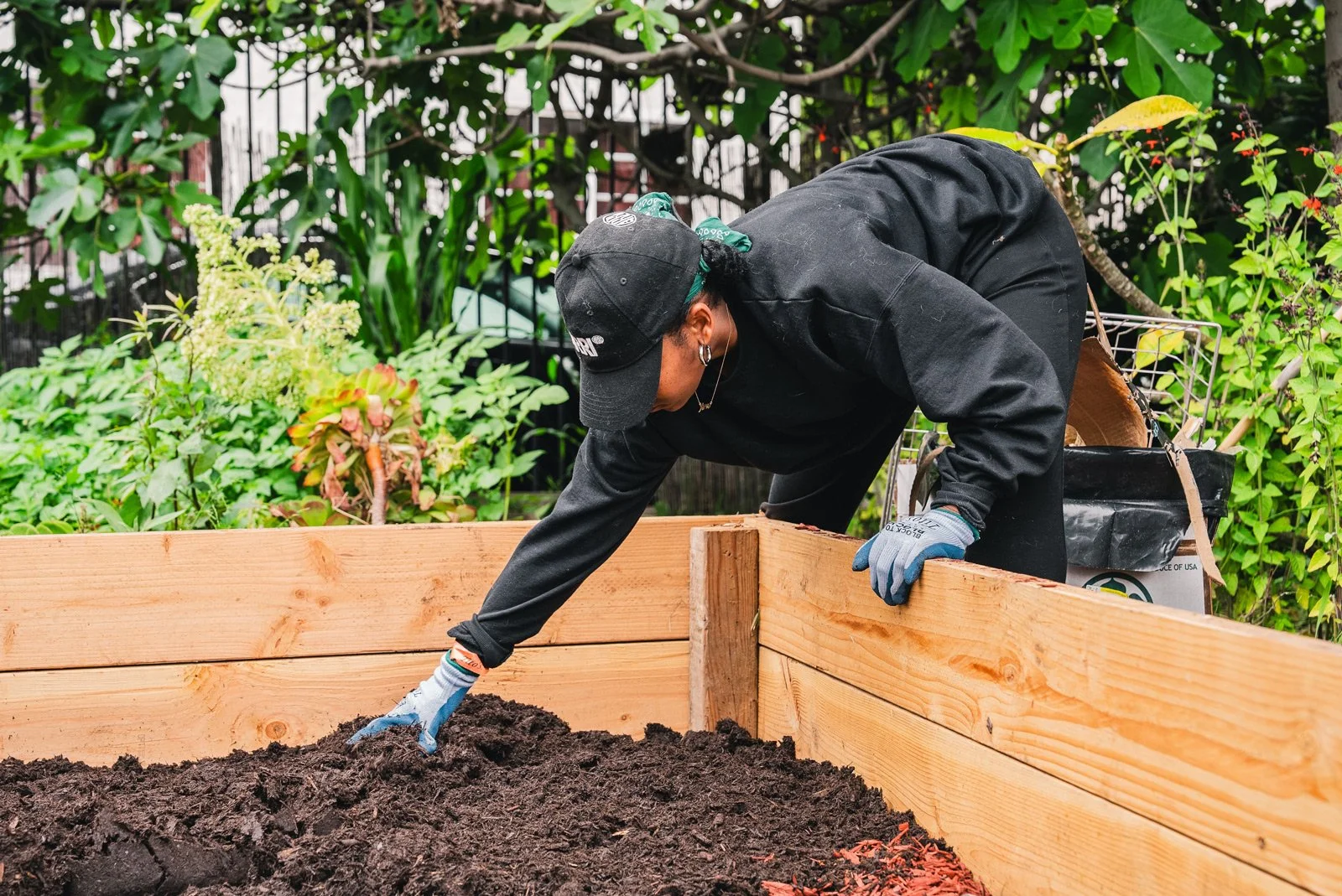 Photo of person bending down to turn the soil in a garden bed