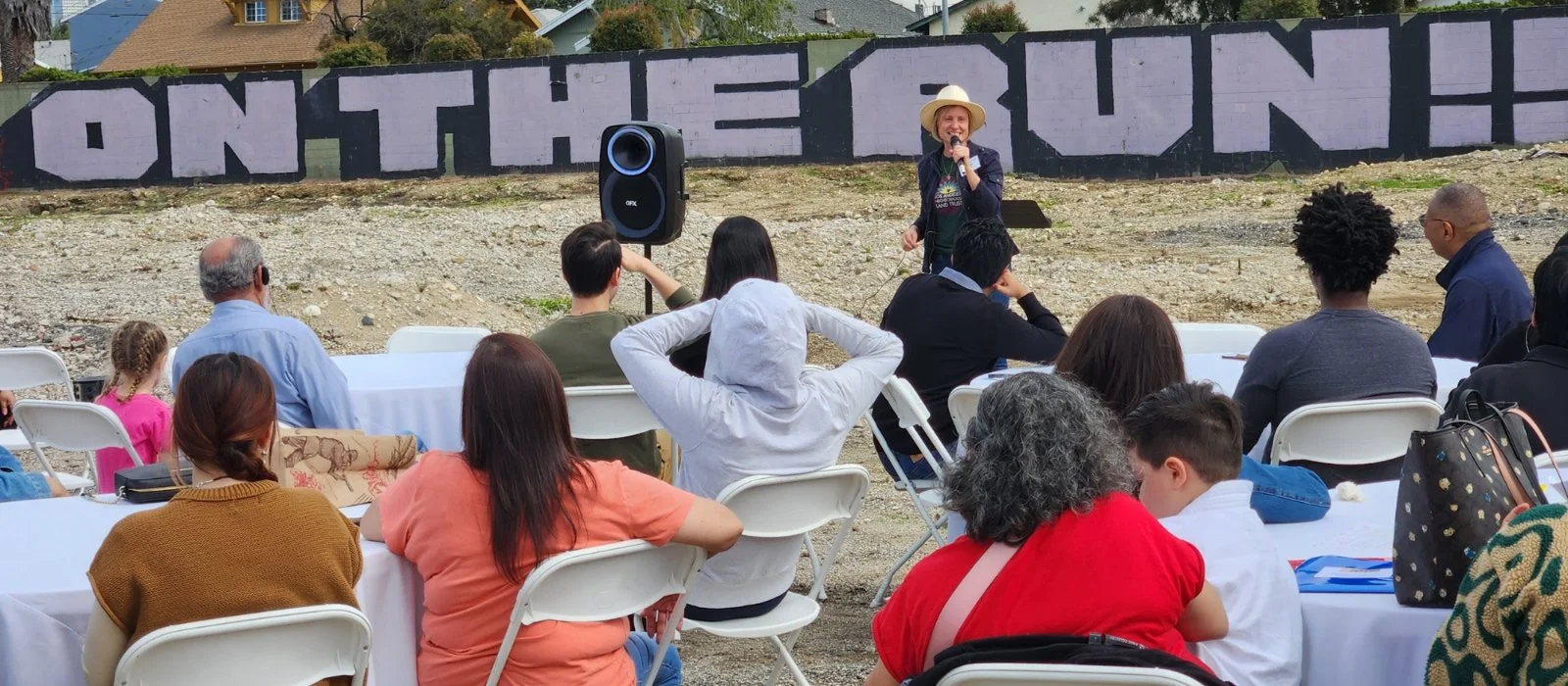 Photo of crowd in a brown field listening to a speaker