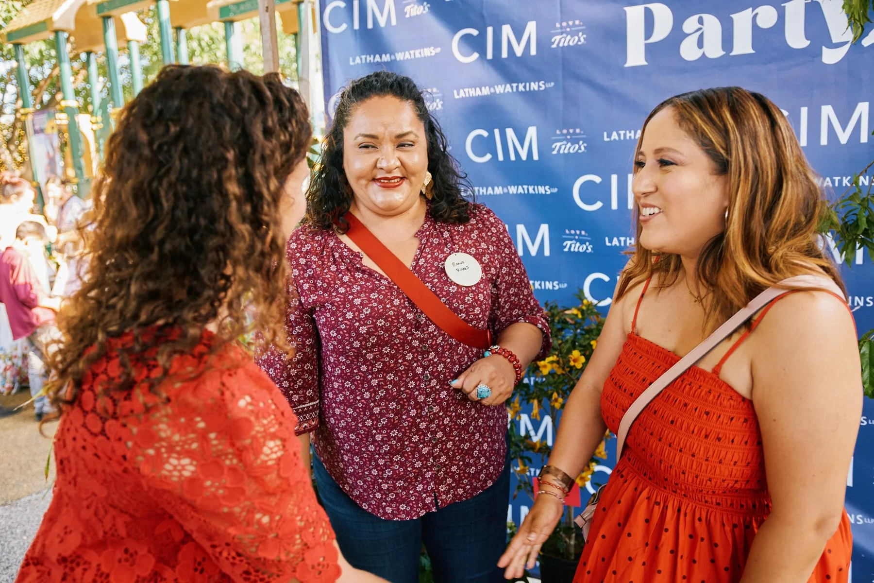 Photo of people talking in front of a step and repeat with CIM and Latham Watkins logo