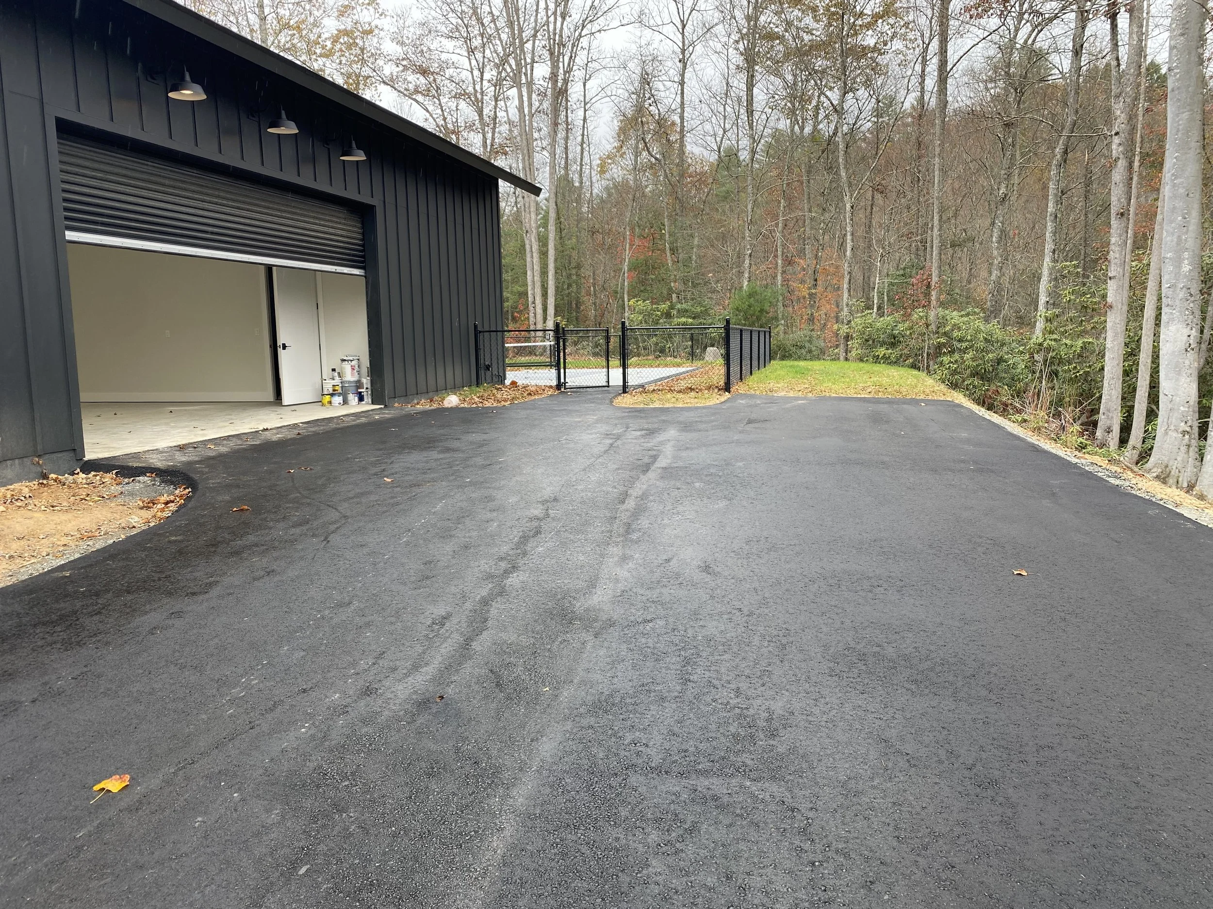 A freshly paved asphalt driveway leading to a large oversized garage at the Barndominium built by Plumb Level Square, LLC in western north carolina