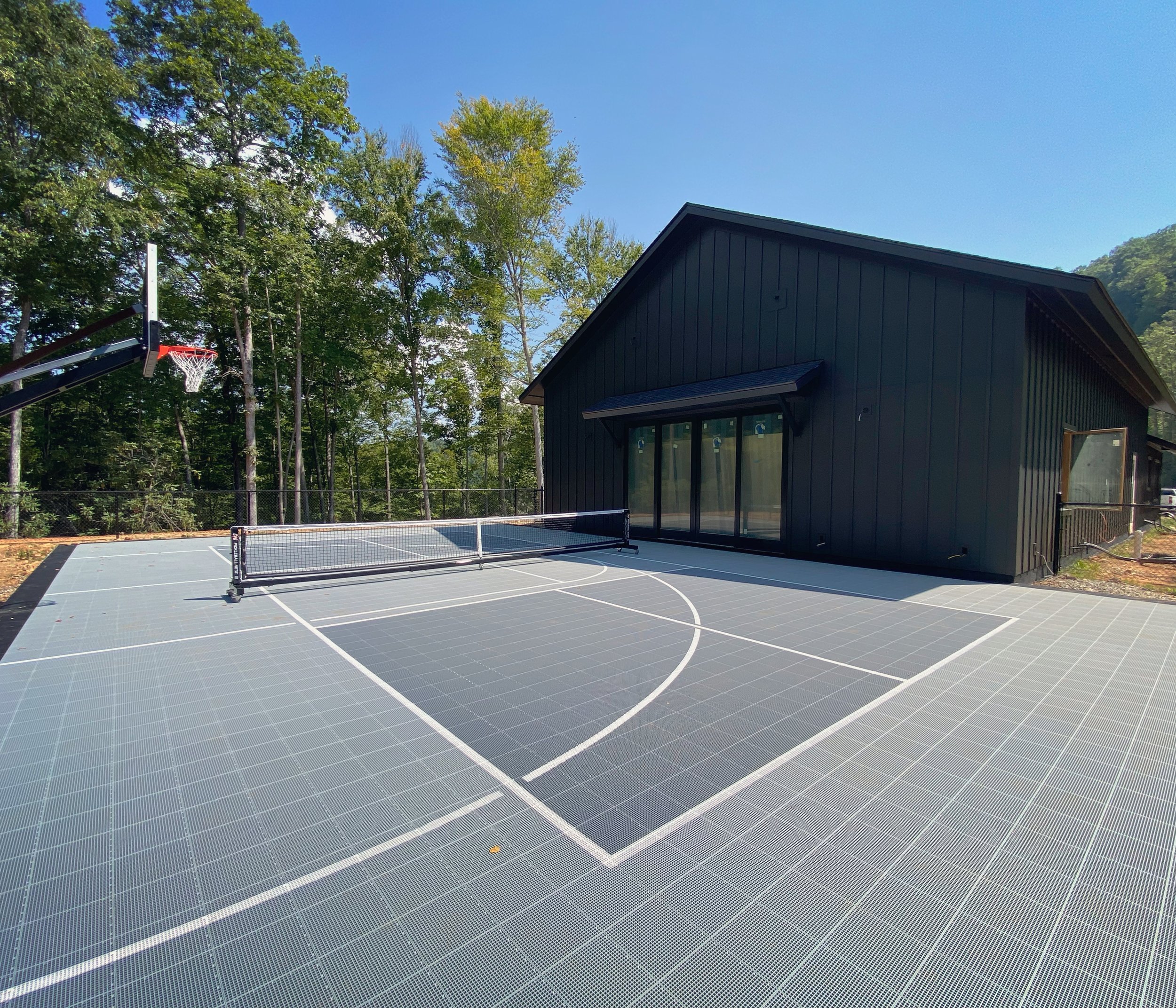 An outdoor pickleball and basketball court at a new build by Plumb Level Square custom home builders in western north carolina