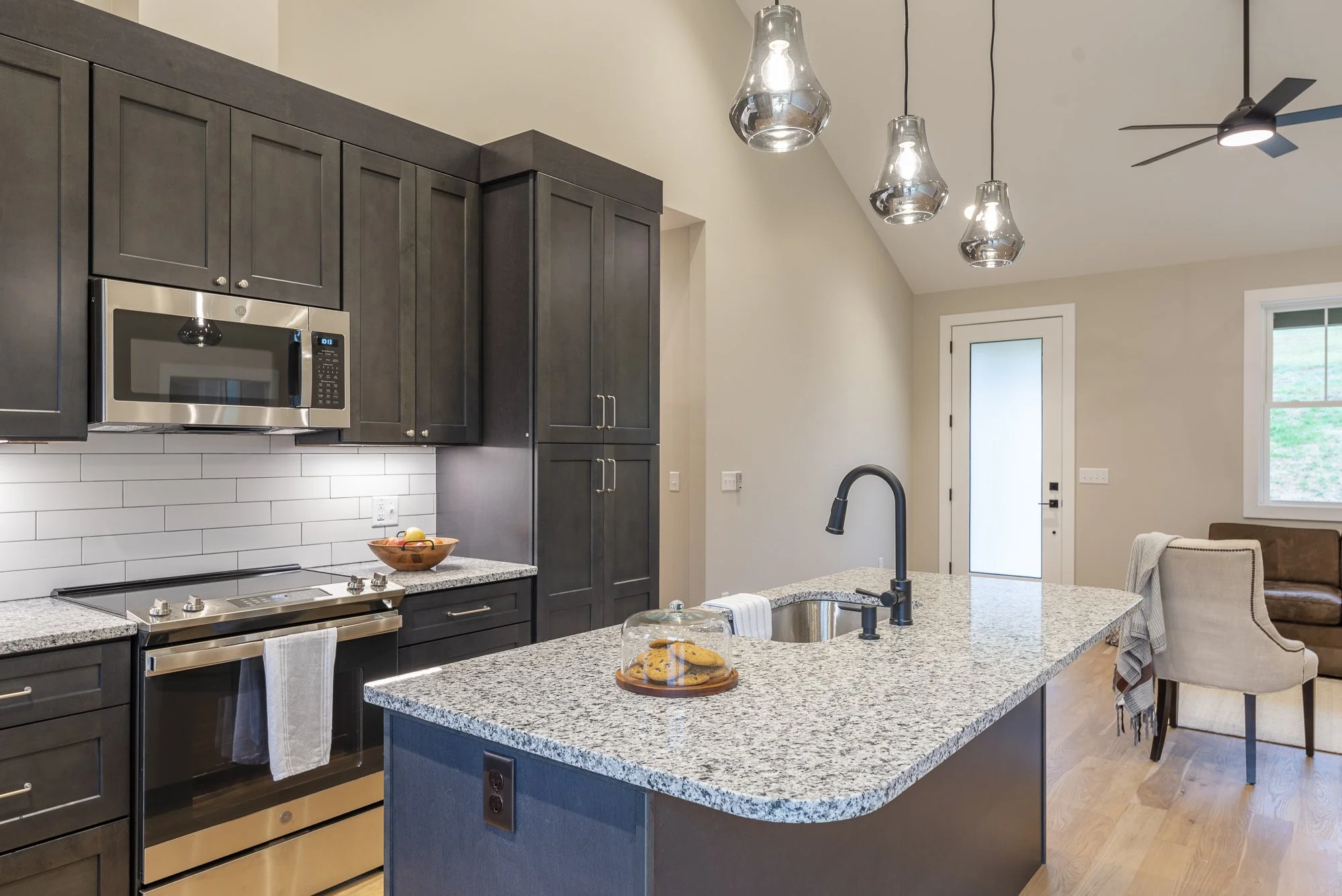 Modern kitchen with dark cabinets, stainless steel appliances, granite countertops by Plumb Level Square builders in Asheville, NC