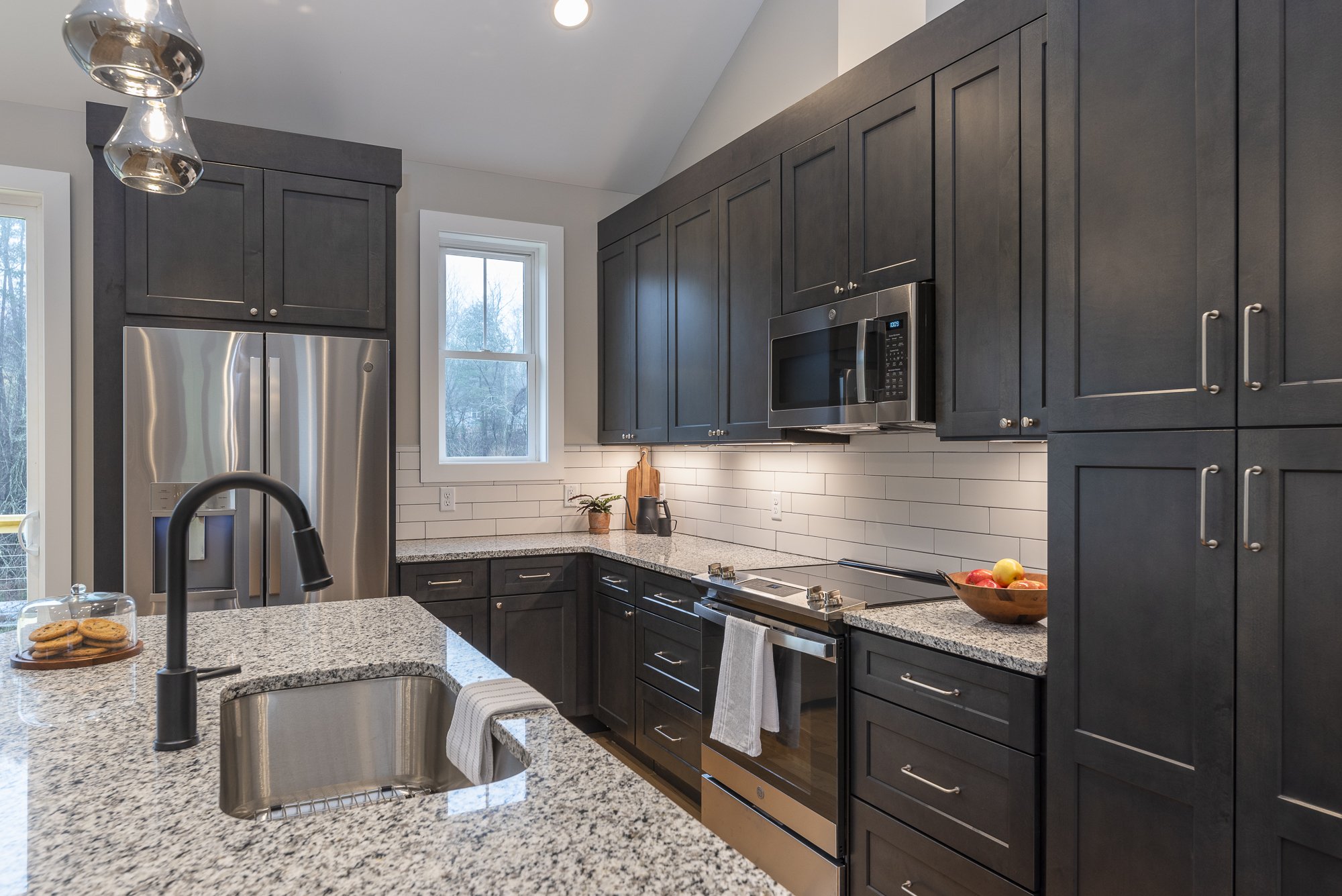 Modern kitchen with dark cabinets, stainless steel appliances, granite countertops by Plumb Level Square builders in Asheville, NC