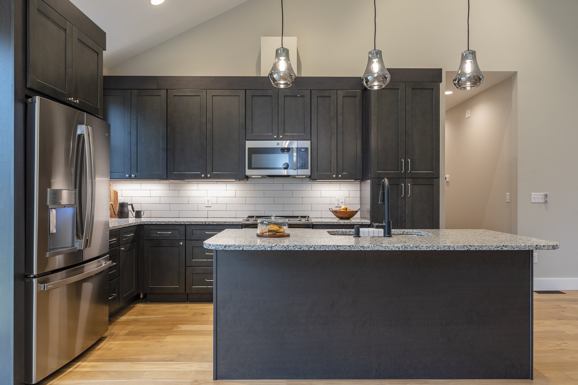 Modern kitchen with dark cabinets, stainless steel appliances, granite countertops by Plumb Level Square builders in Asheville, NC