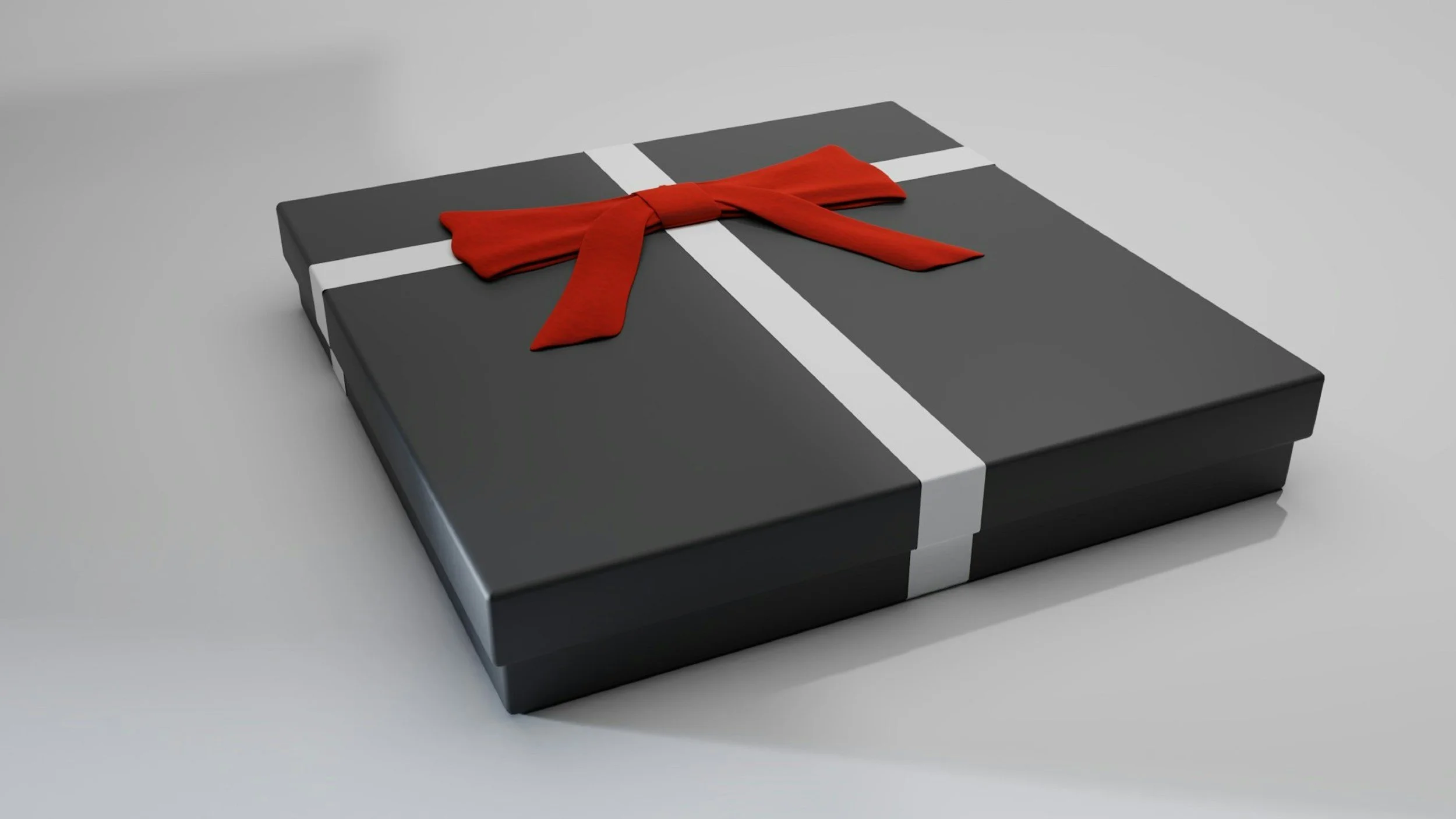 A black gift box with a white ribbon and a red bow on top, placed on a plain grey surface.