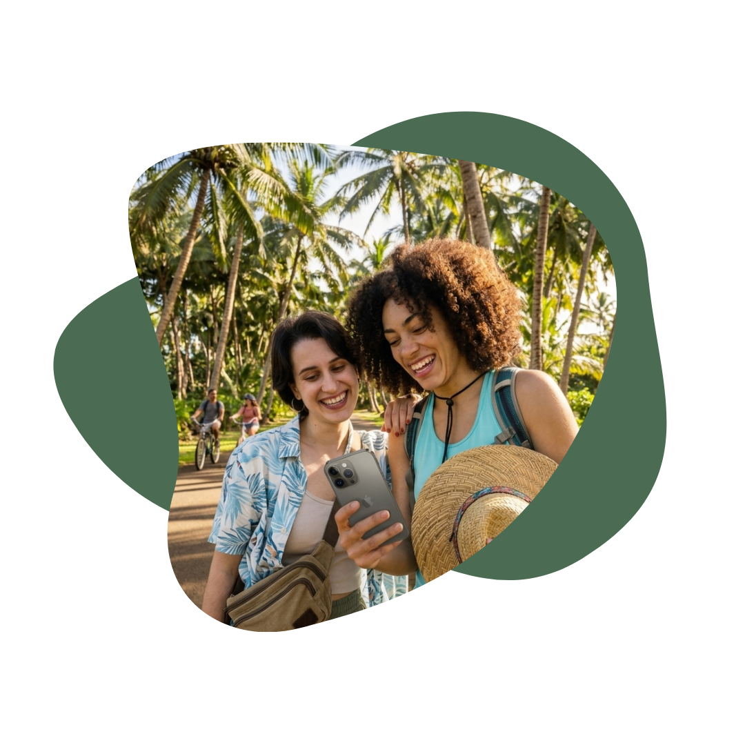 Two women looking at a smartphone together outdoors in a tropical setting