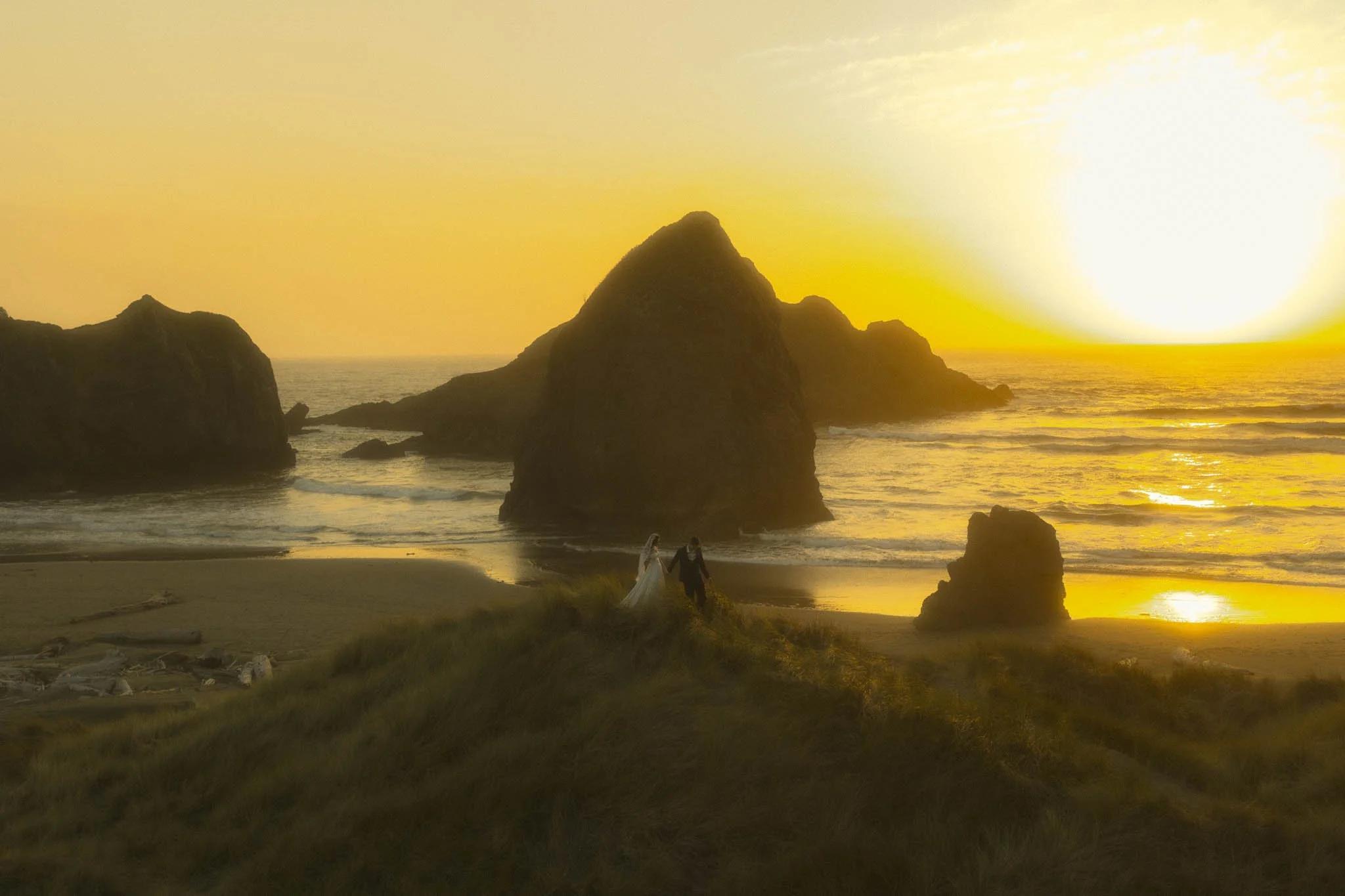 elopement couple walking along the dunes on the Oregon Coast at sunset