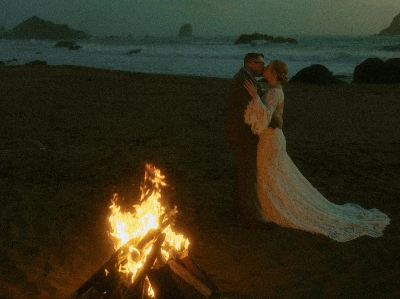 couple sharing a first dance around a beach campfire at sunset on the Oregon Coast