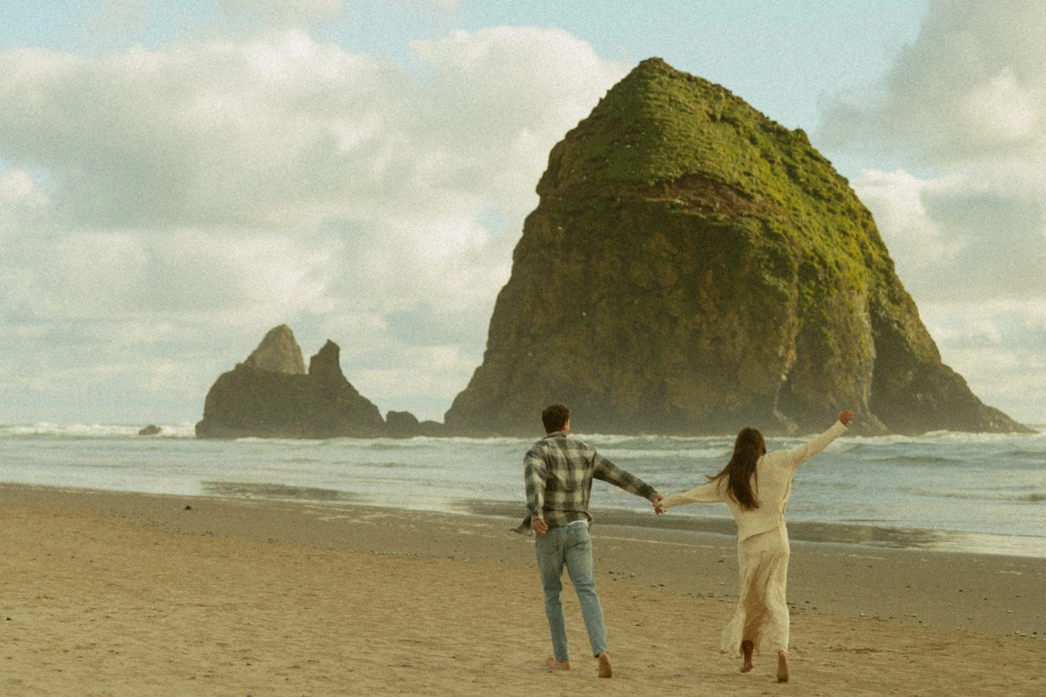couple running on the shore of Cannon Beach in Oregon