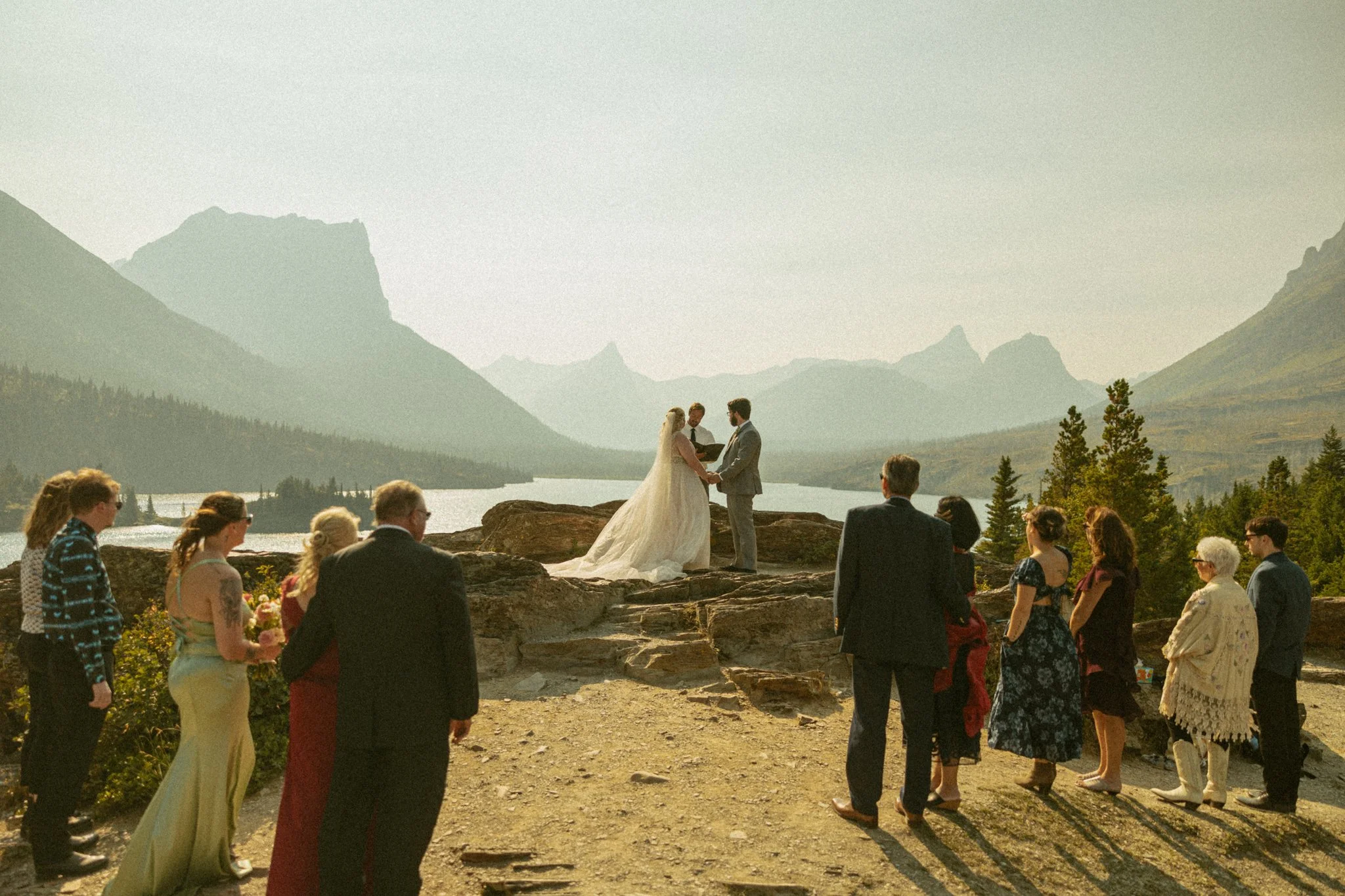 couple getting married cliffside with their family and friends in Montana's Glacier National Park