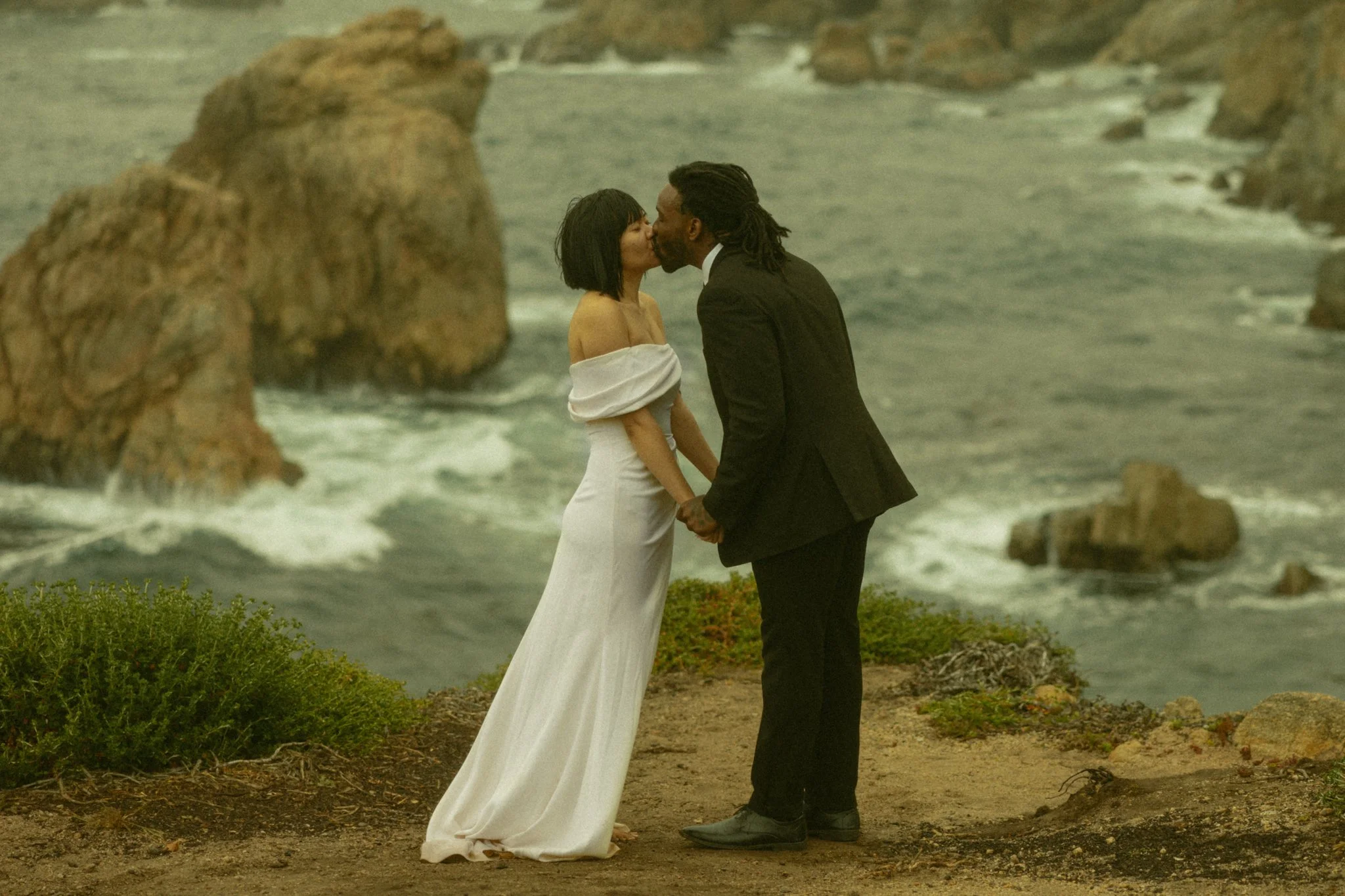 couple sharing a first kiss along the ocean cliff edges in California's Big Sur