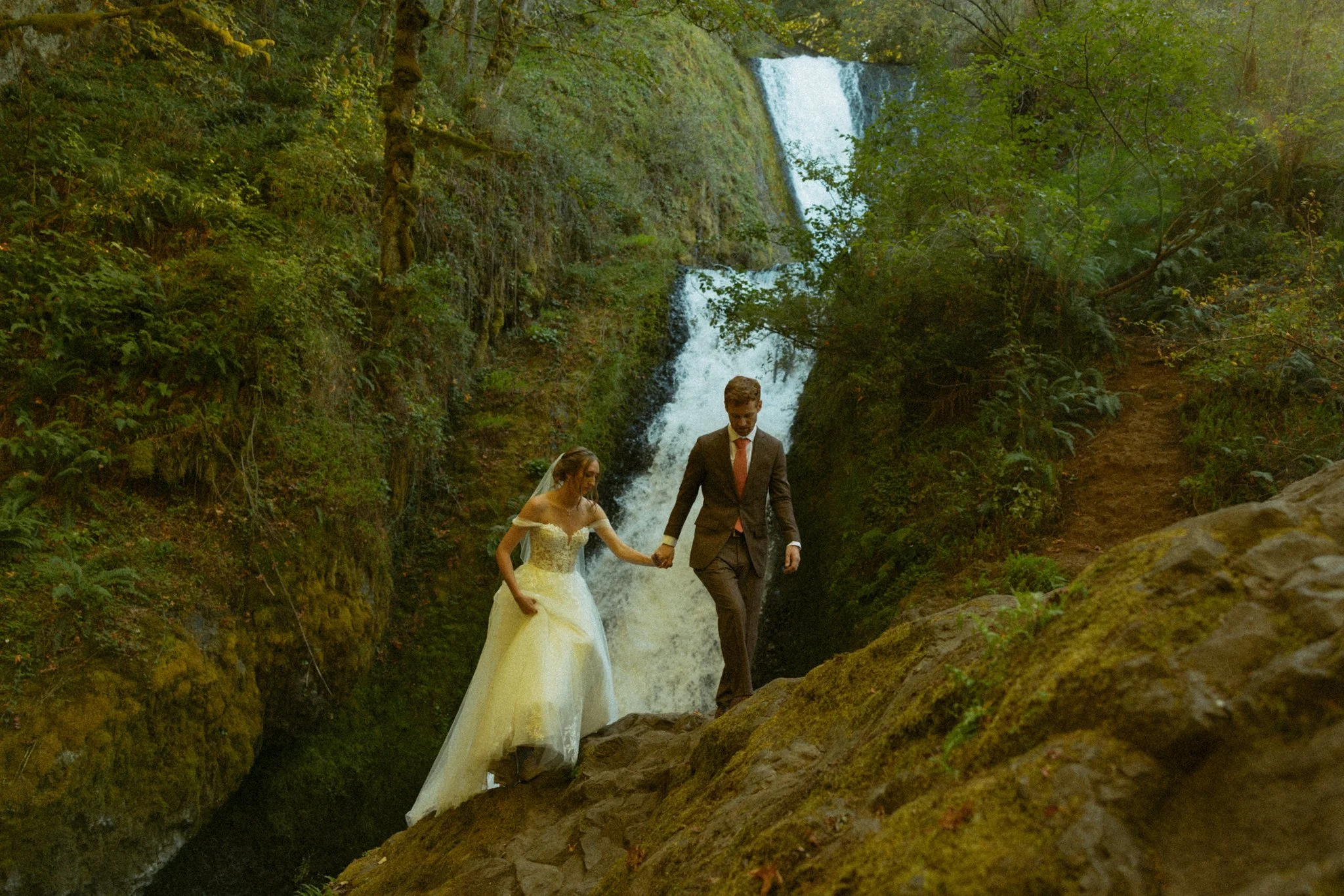 elopement couple climbing boulder at Bridal Veil Falls in the Columbia River Gorge