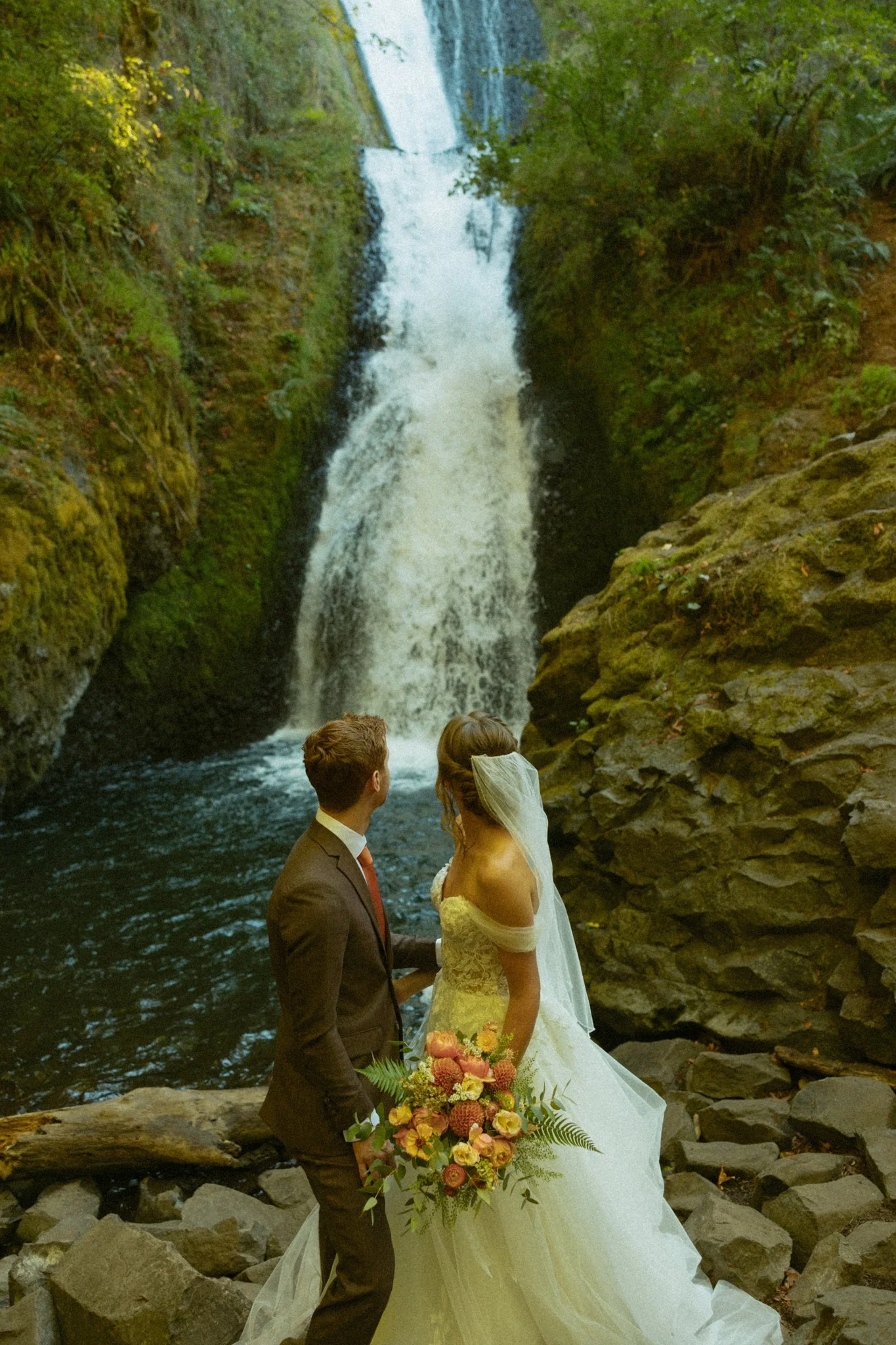 an elopement couple standing beneath Bridal Veil Falls in the Columbia River Gorge