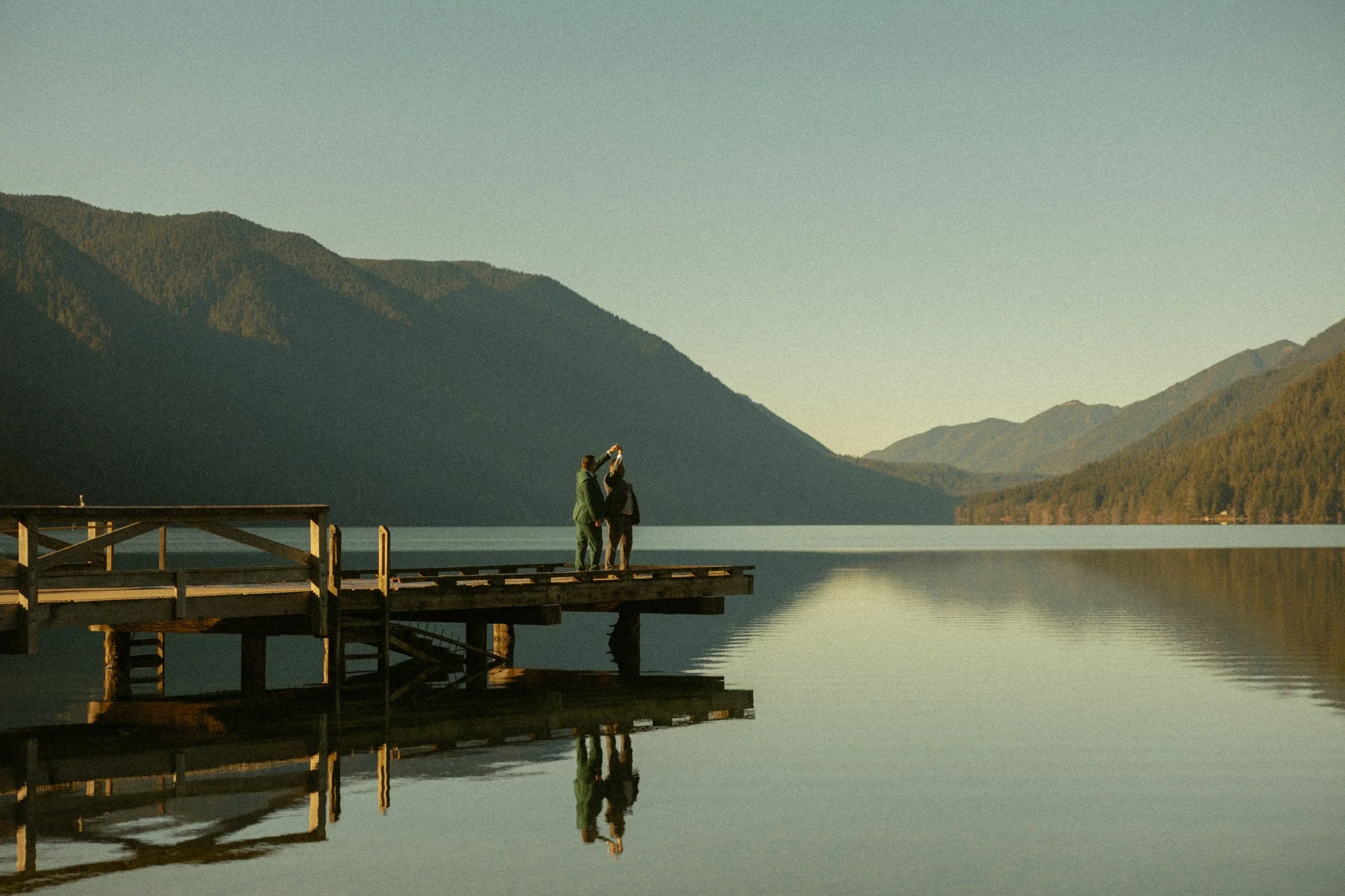 elopement couple twirling on dock at Lake Crescent Lodge