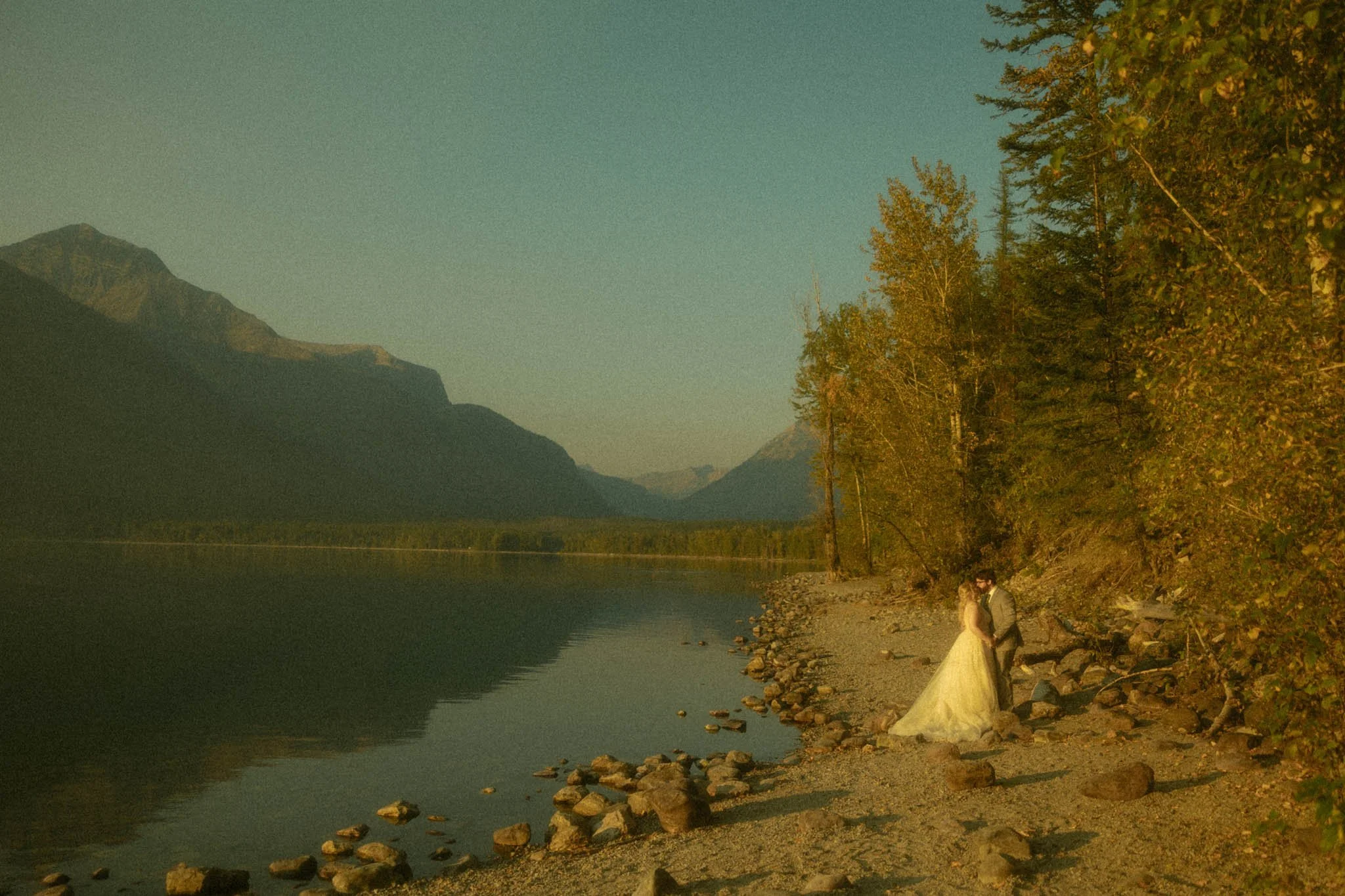 an elopement couple kissing on the lakeshore of Lake McDonald in Glacier National Park