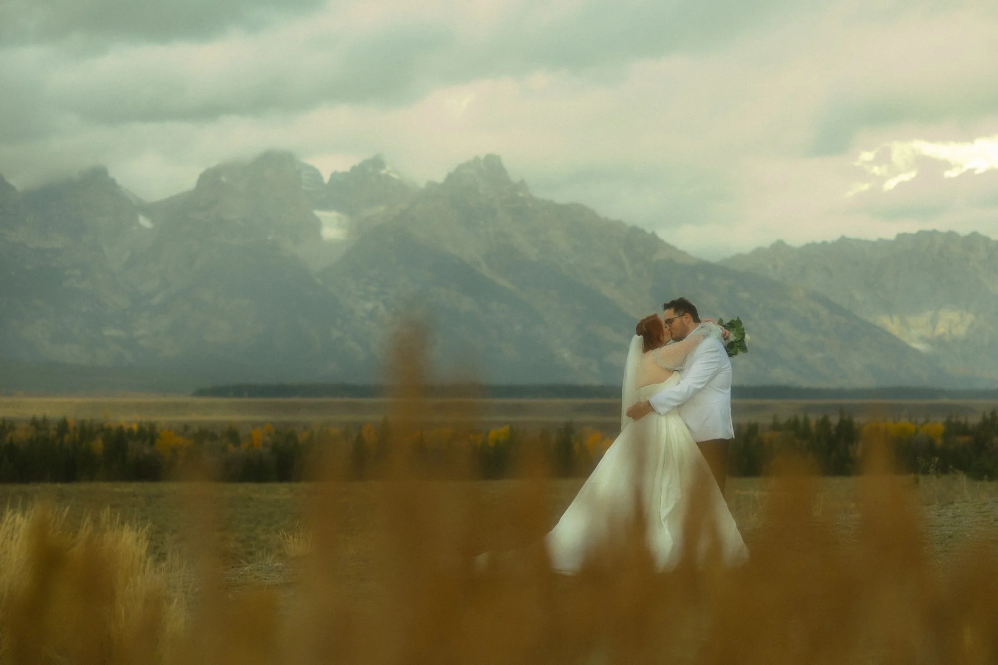 an elopement couple kissing with the Grand Tetons behind them