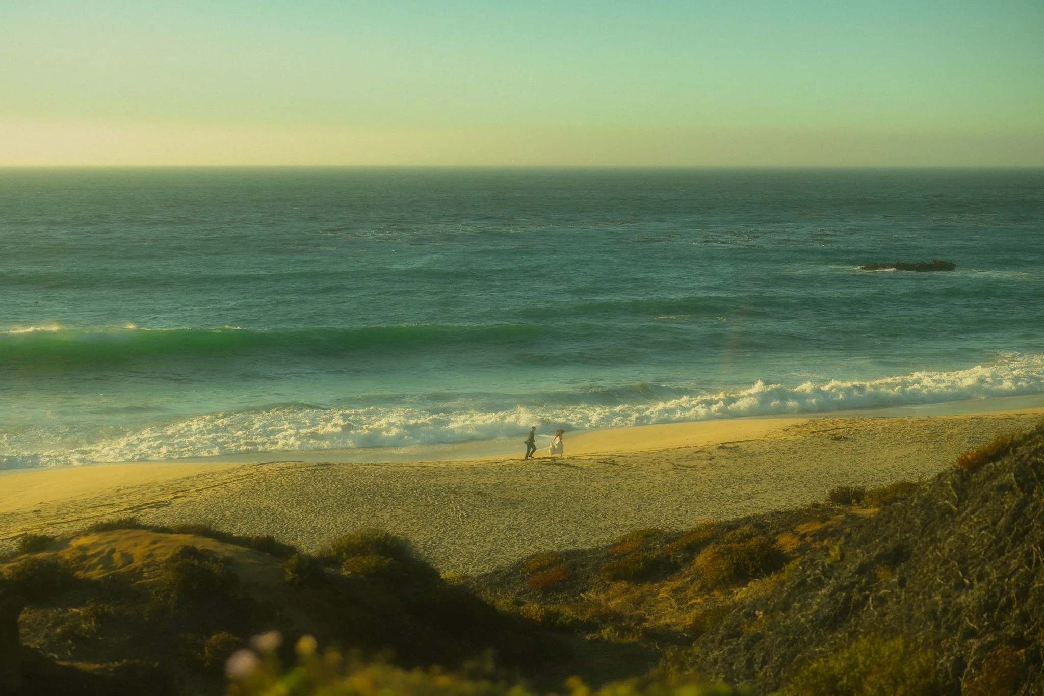 an elopement couple playfulling running along the beach in Big Sur