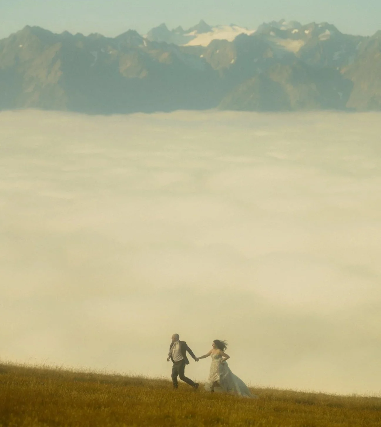 elopement couple running along mountain ridge in Hurricane Ridge of Olympic National Park