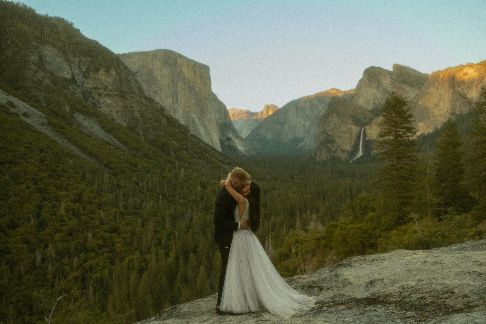 couple kissing on cliff edge overlooking Tunnel View in California's Yosemite National Park