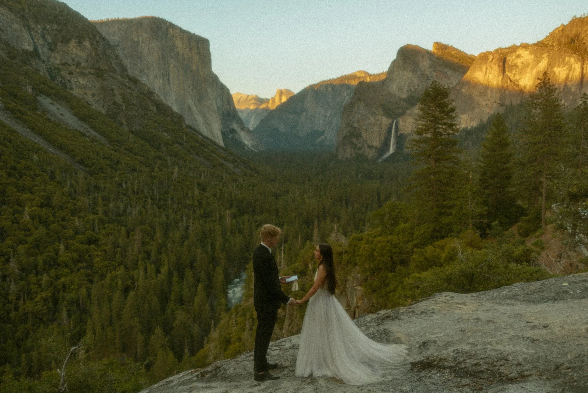 couple saying their vows on cliff edge overlooking Tunnel View in California's Yosemite National Park