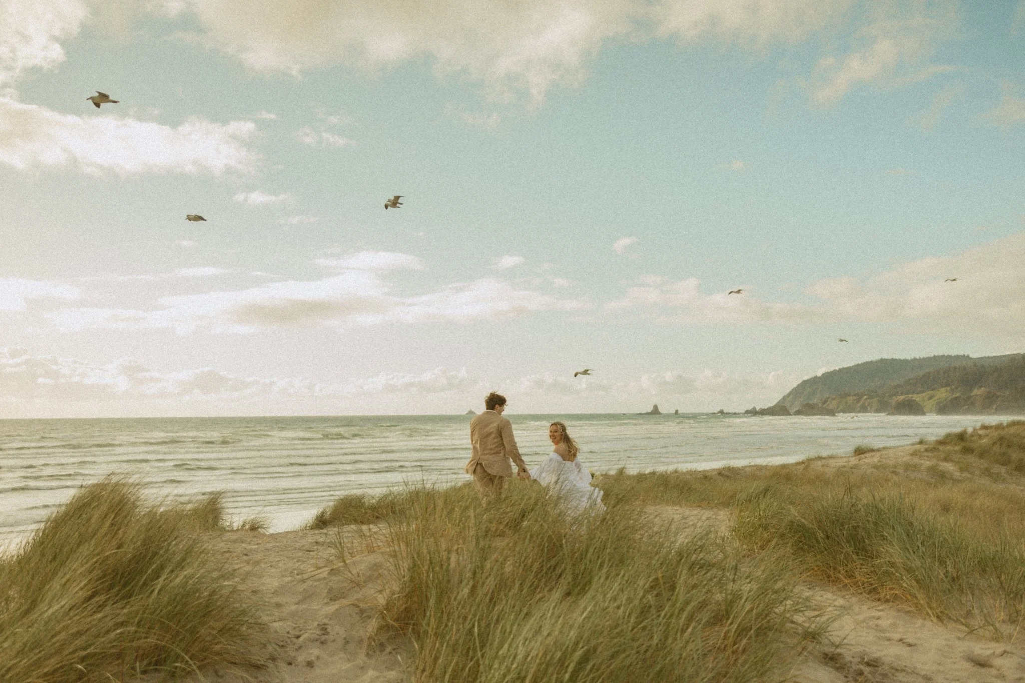 elopement couple running on beach sand dunes along the Oregon Coast