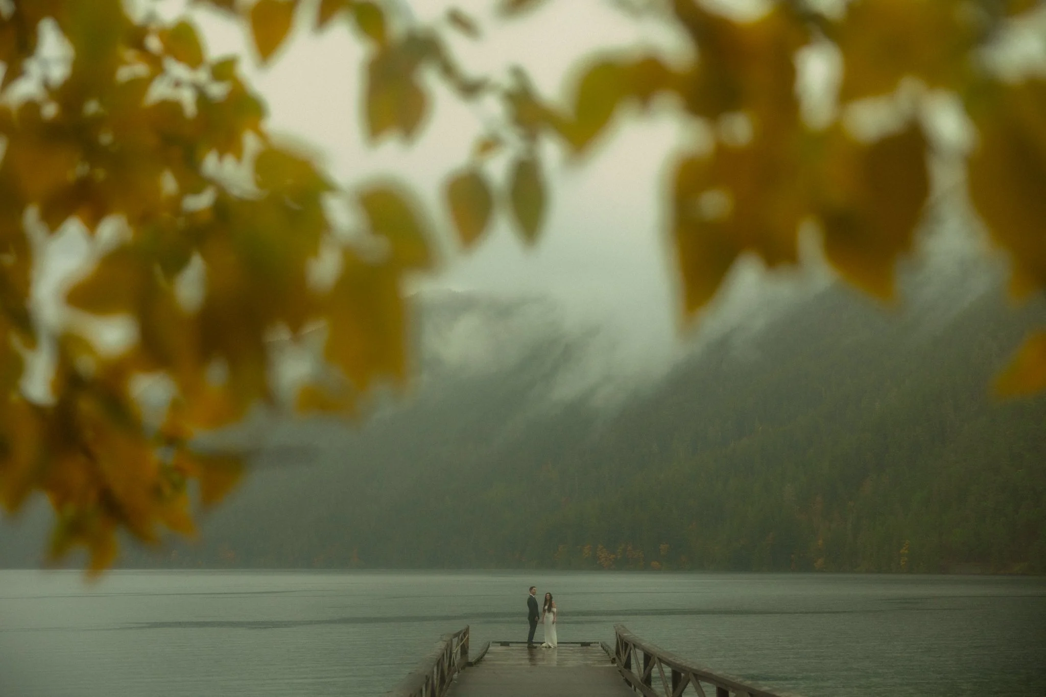 an elopement couple standing on the Lake Crescent Lodge dock in the rain