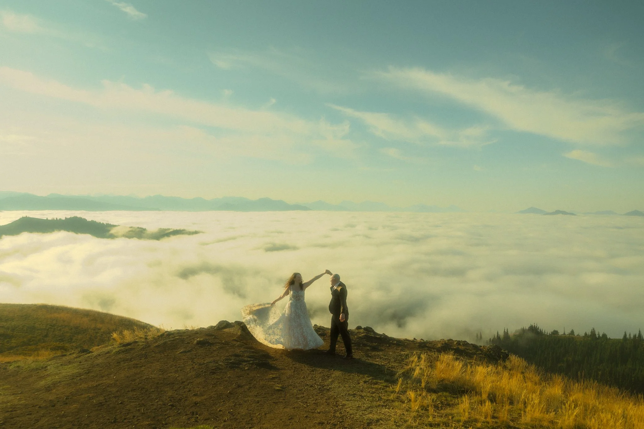 an elopement couple twirling above the clouds on a mountain top in Olympic National Park