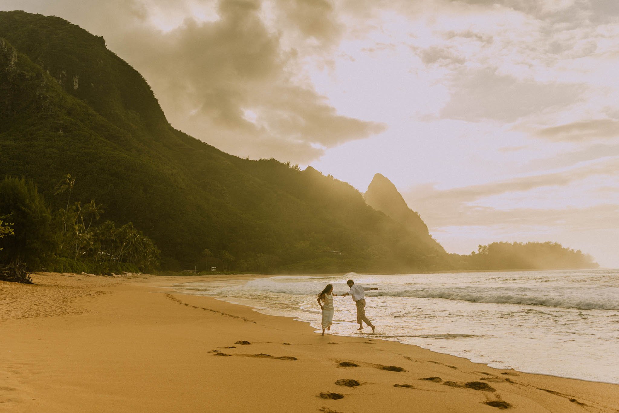 a wedding couple running on the beach at sunset in Hawaii