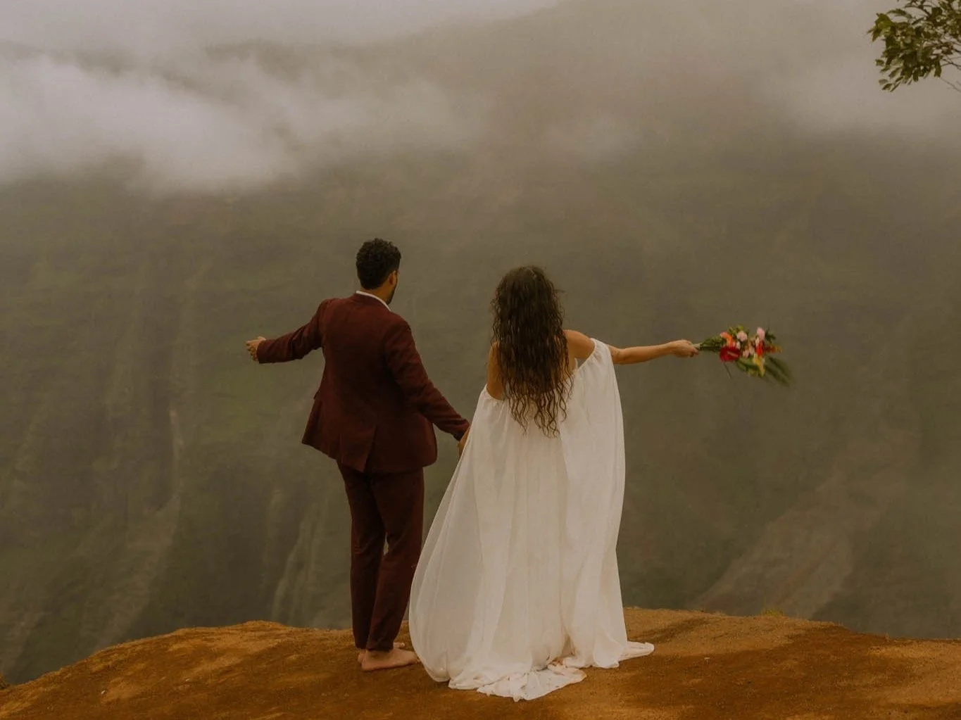 a couple cheering on a cliffside in Hawaii after their ceremony