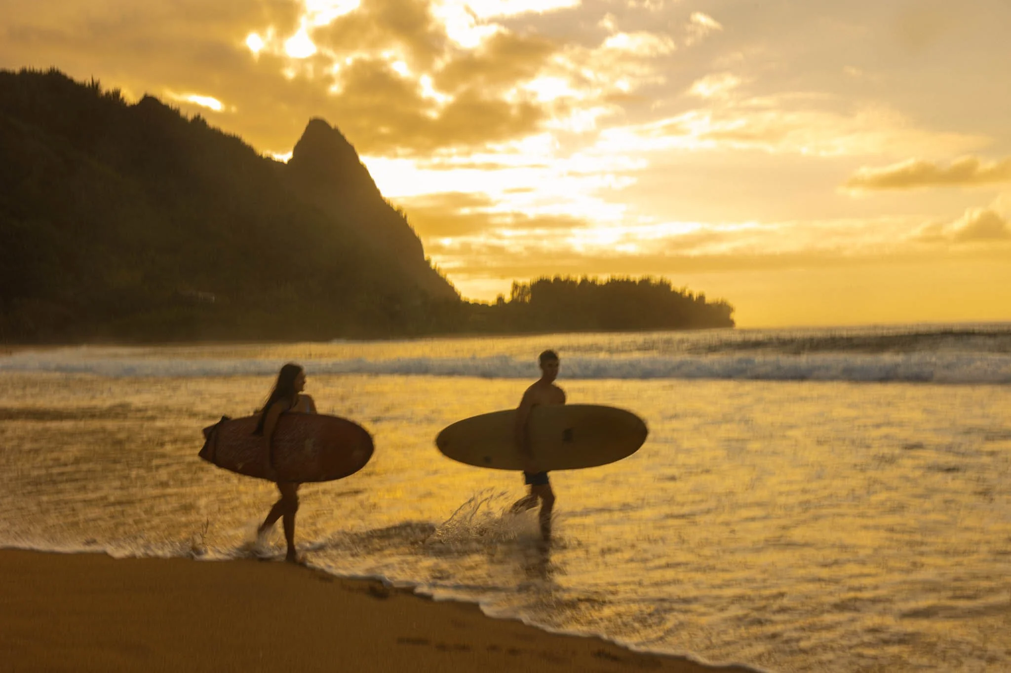 an elopement couple surfing at sunset together